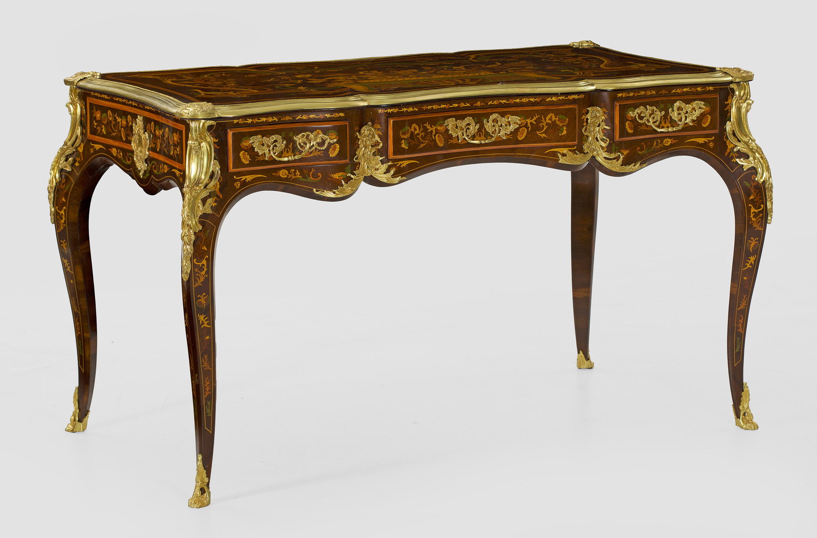 Bureau plat im Louis XV-Stil: Nussbaum, furniert sowie Einlagen aus unterschiedlichen, teilw. gefärbten Hölzern. Passig geschweifter Zargenkasten auf stark geschwungenen Beinen. In der gegliederten Front drei Schubladen untersch