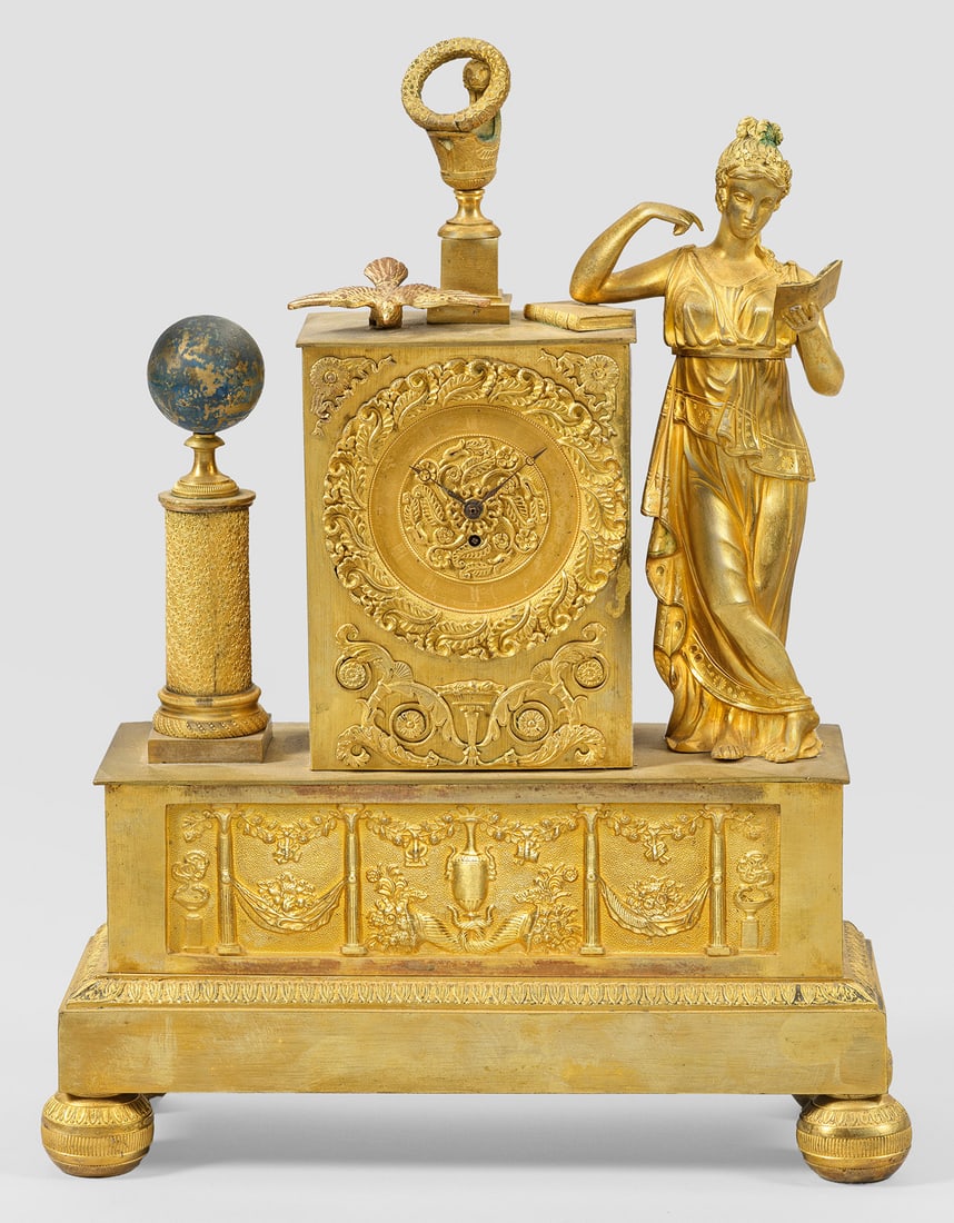 Charles X-Pendule: Bronze, vergoldet. Über querrechteckig, schauseitig reliefiertem Sockel auf Kugelfüßen vollplastische Darstellung einer Lesenden mit Globus, das rechteckige floral reliefierte Uhrengehäuse flankie