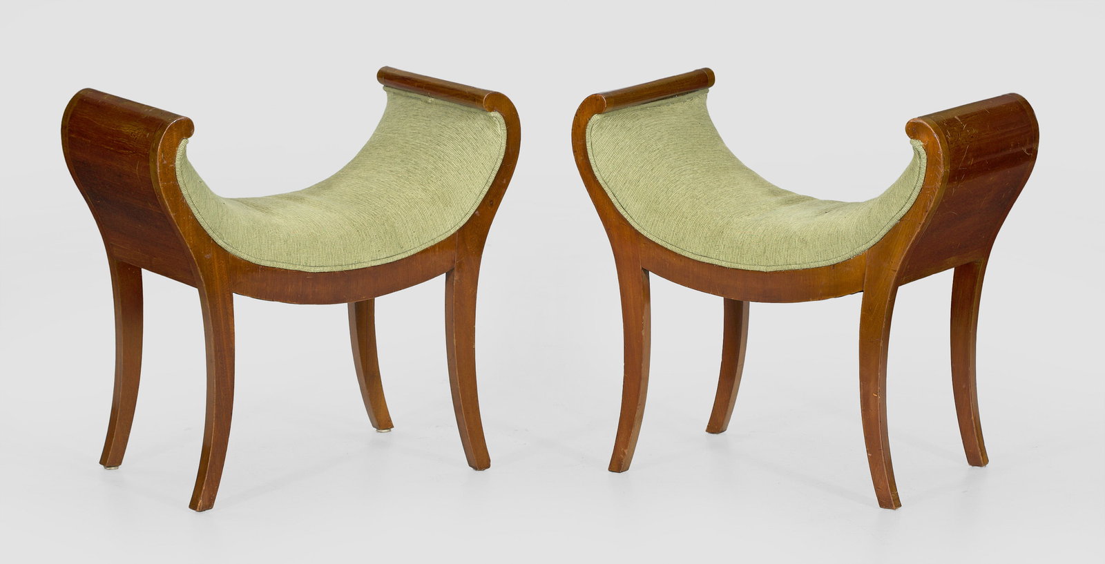Paar Gondelhocker: Mahagoni, furniert. Gebogte Zarge auf leicht ausgestellten Vierkantbeinen, in volutenförmige Armlehnen übergehend. Gepolstert und bezogen. H. 57 cm. 60 cm x 33 cm. Sitz-H. 38 cm. Provenienz: Collect