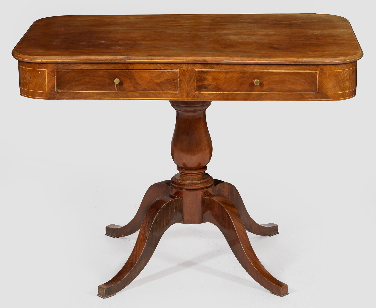 Biedermeier-Salontisch: Mahagoni, furniert sowie schmale Einlagen aus Ahorn. Über mehrfach gegliedertem Balusterschaft und stark geschwungenen Beinen, rechteckig angelegter, zweischübiger Zargenkasten mit gerundeten Ecken.