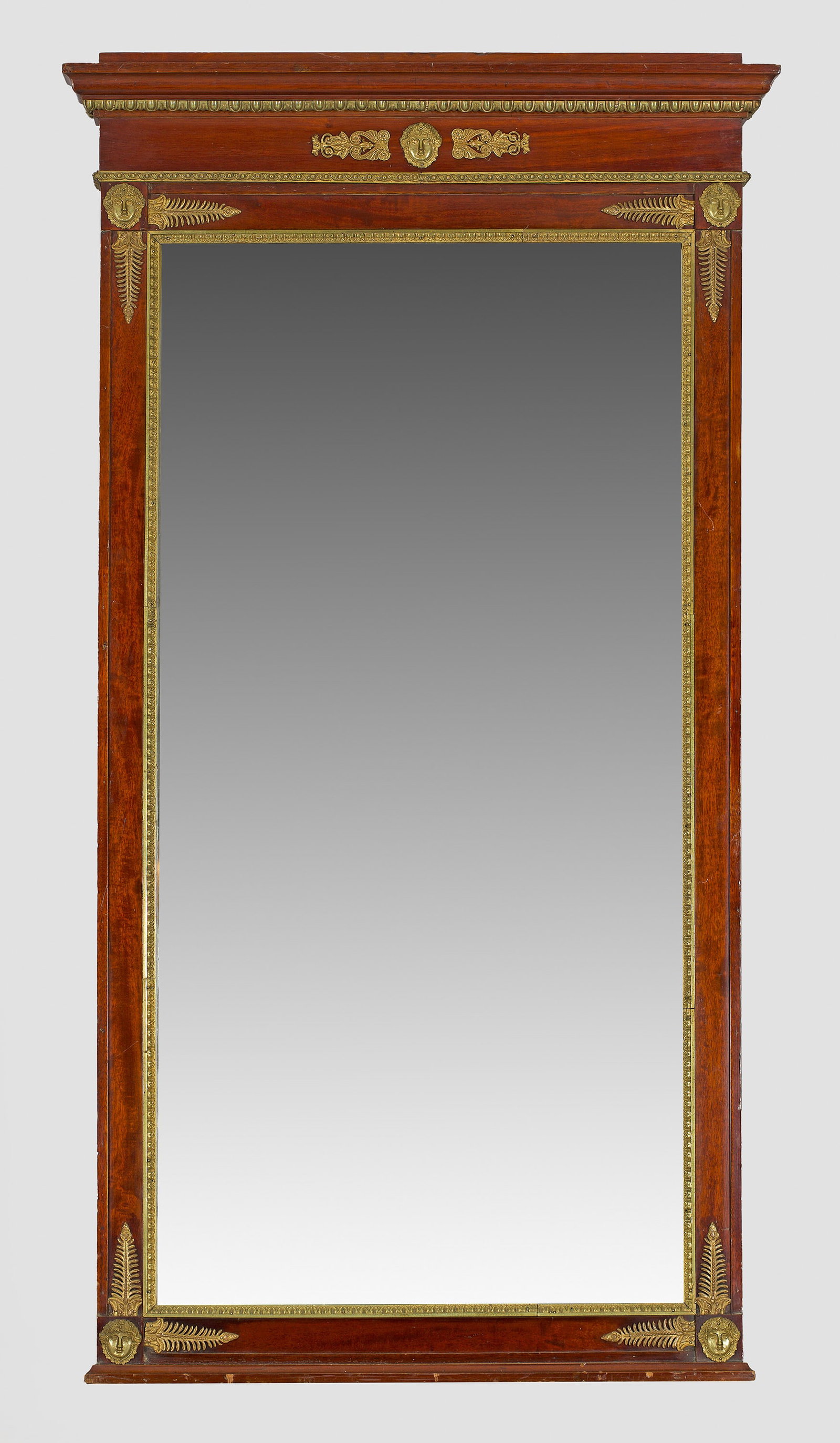 Großer Empire-Wandspiegel: Mahagoni, furniert sowie Applikationen aus Bronze. Gerade, hochrechteckige Spiegelrahmung mit schmalem Palmettenfries. Oberhalb schmales Giebelfeld sowie profiliertes Gesims. Facettierte Spiegelfläch