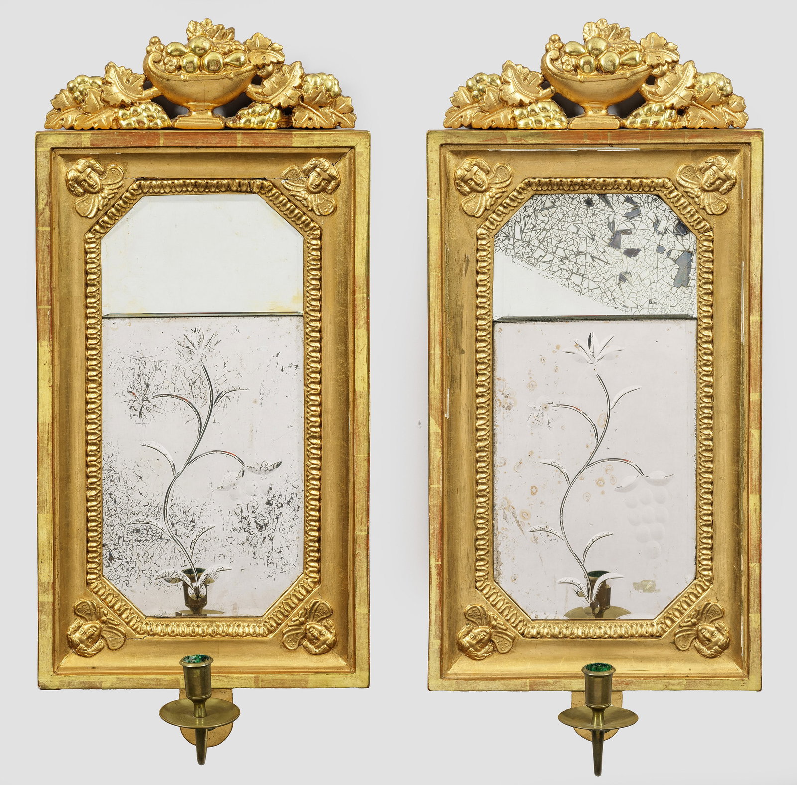Paar gustavianische Spiegelappliken: 1-flg.; Holz, gefasst und vergoldet sowie Messing. Hochrechteckige, profilierte Spiegelrahmung mit Bekrönung in Form eines erhaben reliefierten Vasenmotivs. Unterhalb davon ausgehend geschwungener Le
