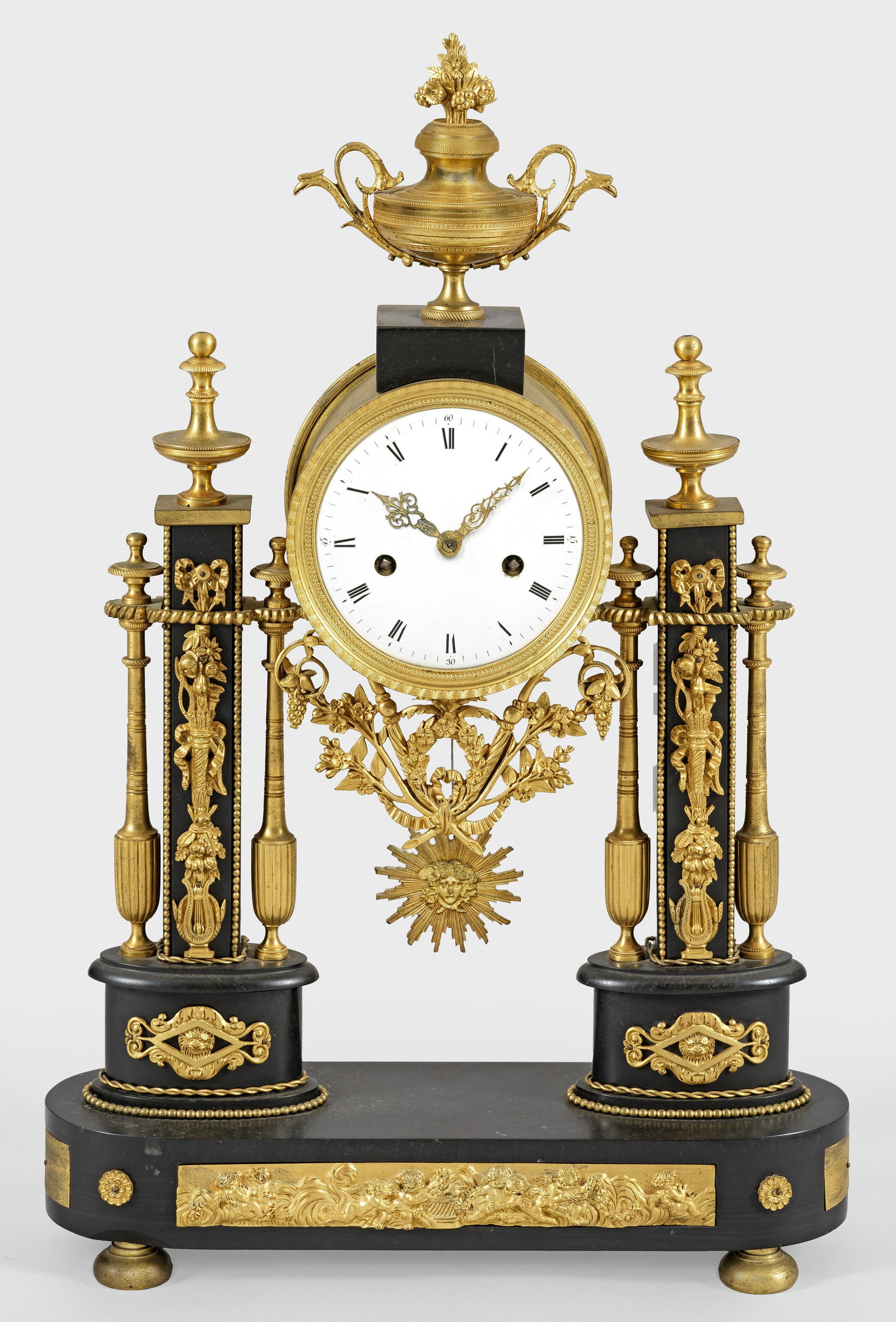 Louis XVI-Portaluhr: Schwarzer Marmor sowie vergoldete Bronze. Über gerundetem Sockel mit reliefiertem Puttenfries und gedrückten Füßen architektonisch gegliederter Korpus als Träger für rundes Uhrengehäuse mit Vas