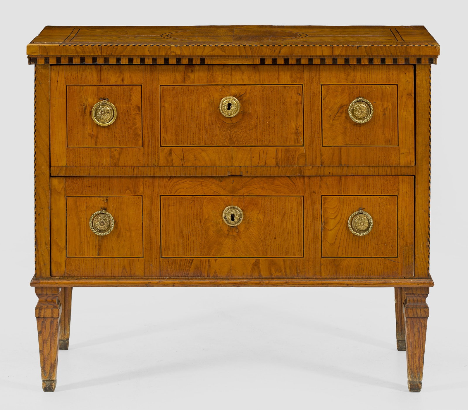 Louis XVI-Kommode: Eschenholz, furniert. Gerader, querrechteckig angelegter Korpus auf schmaler Zarge und kannelierten Balusterbeinen. In der gegliederten Front zwei breite Schubladen. Gering überstehende Deckplatte mi