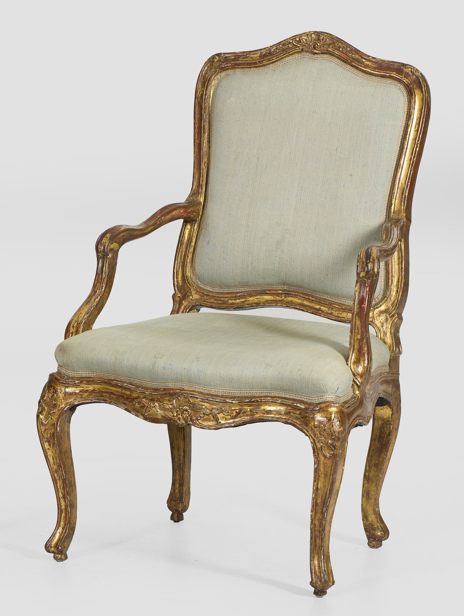 Louis XV-Armlehnsessel: Holz, geschnitzt, gefasst und vergoldet. Passig geschweifte Zarge mit erhaben reliefierten Rocaillen in korrespondierende Beine übergehend. Entsprechende Stütze für schmale Armlehnen. Leicht zurüc