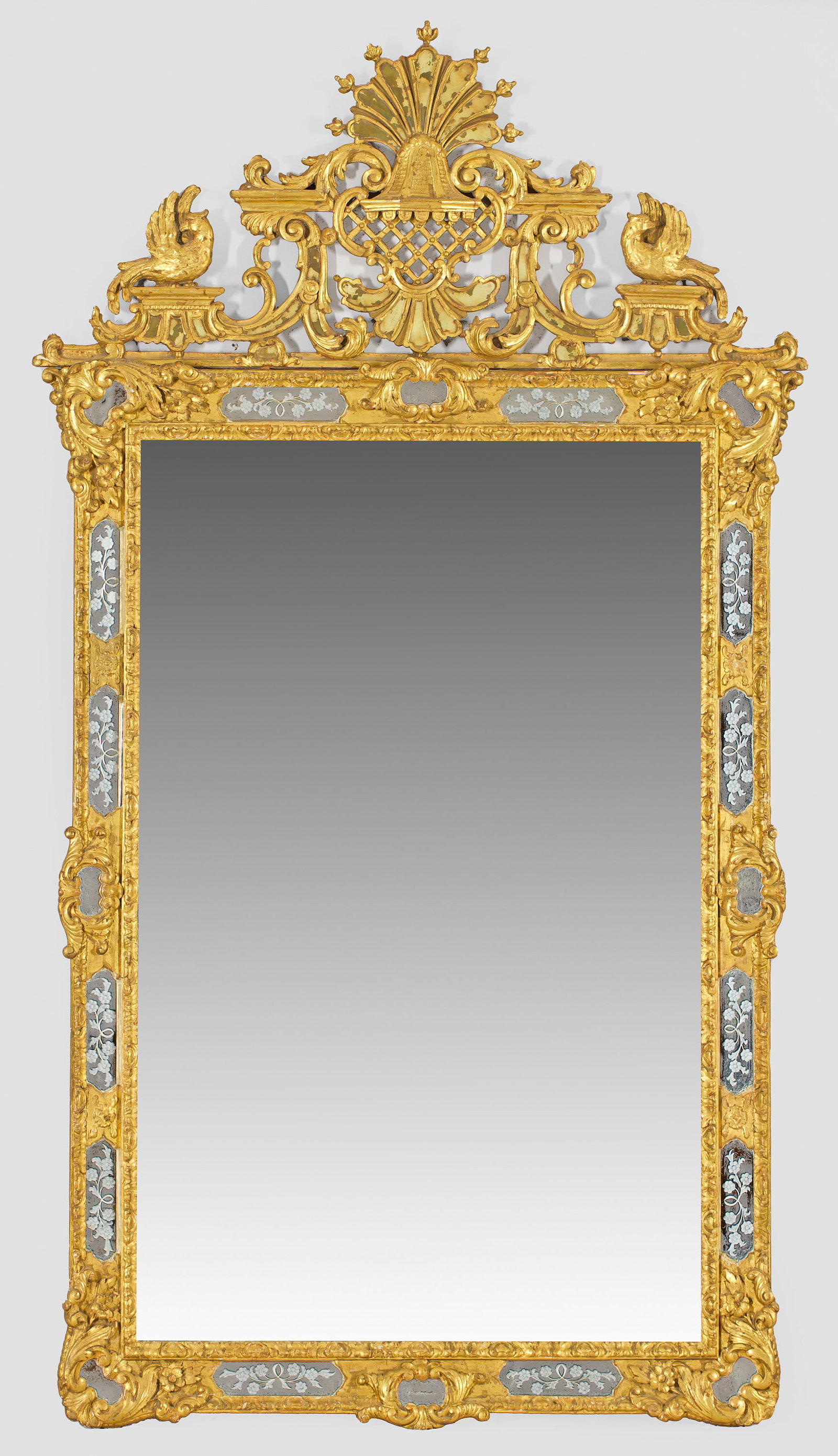 Großer Barock-Wandspiegel: Holz, geschnitzt, gefasst und vergoldet. Hochrechteckige, offen gestaltete Spiegelrahmung aus schmalen Streben und floral ornamentierten Spiegelelementen, durch Blattkartuschen verbunden. Hohe, durchb