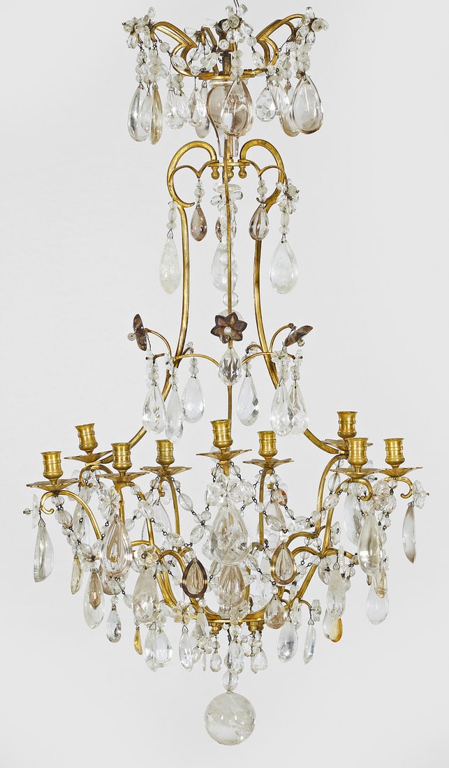 Louis XV-Deckenlüster mit Bergkristallbehang: 9-flg.; Bronze, vergoldet sowie geschliffener Bergkristall und farbloses bzw. quarzfarbenes Kristallglas. Balusterförmiger, offen gestalteter Korpus aus schmalen, stark geschwungenen, volutenförmig 