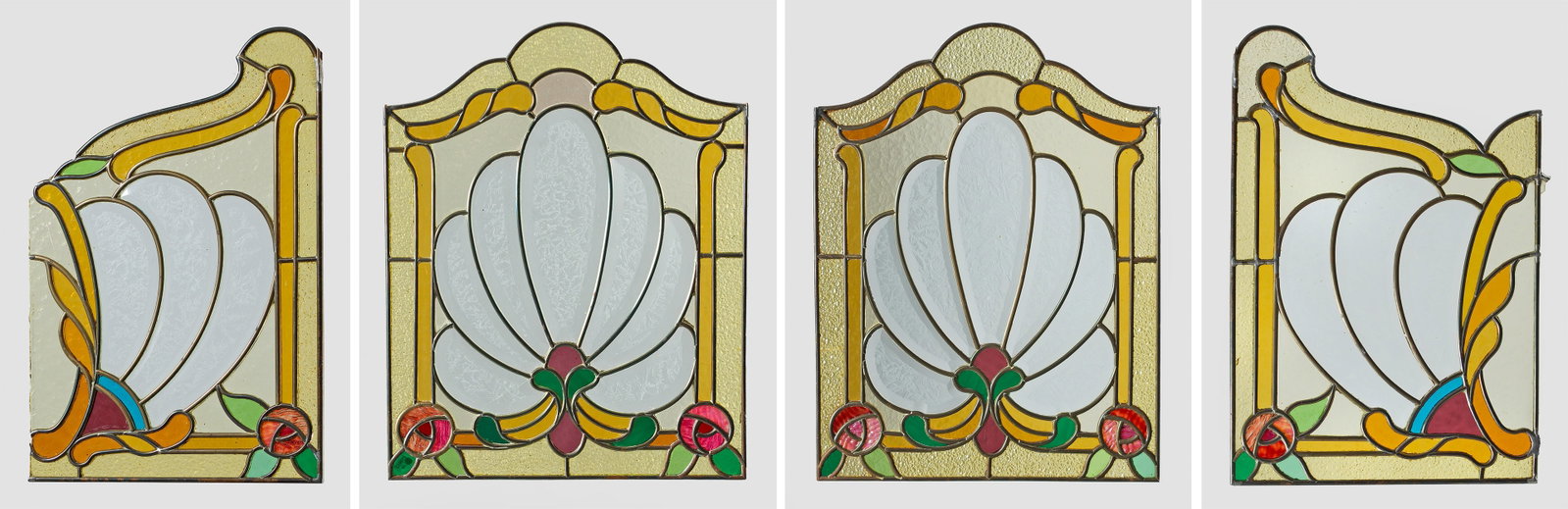 Florale Jugendstil-Bleiglasfenster: 4-tlg.; Rechteckige, oberhalb geschweifte Form. Farbloses, teilw. polychromes und geriffeltes Glas in blütenförmiger Gestalt mit kleinen Eckblumen. Messingaufhängung. Minim. best.; H. 50 cm x 37,5 