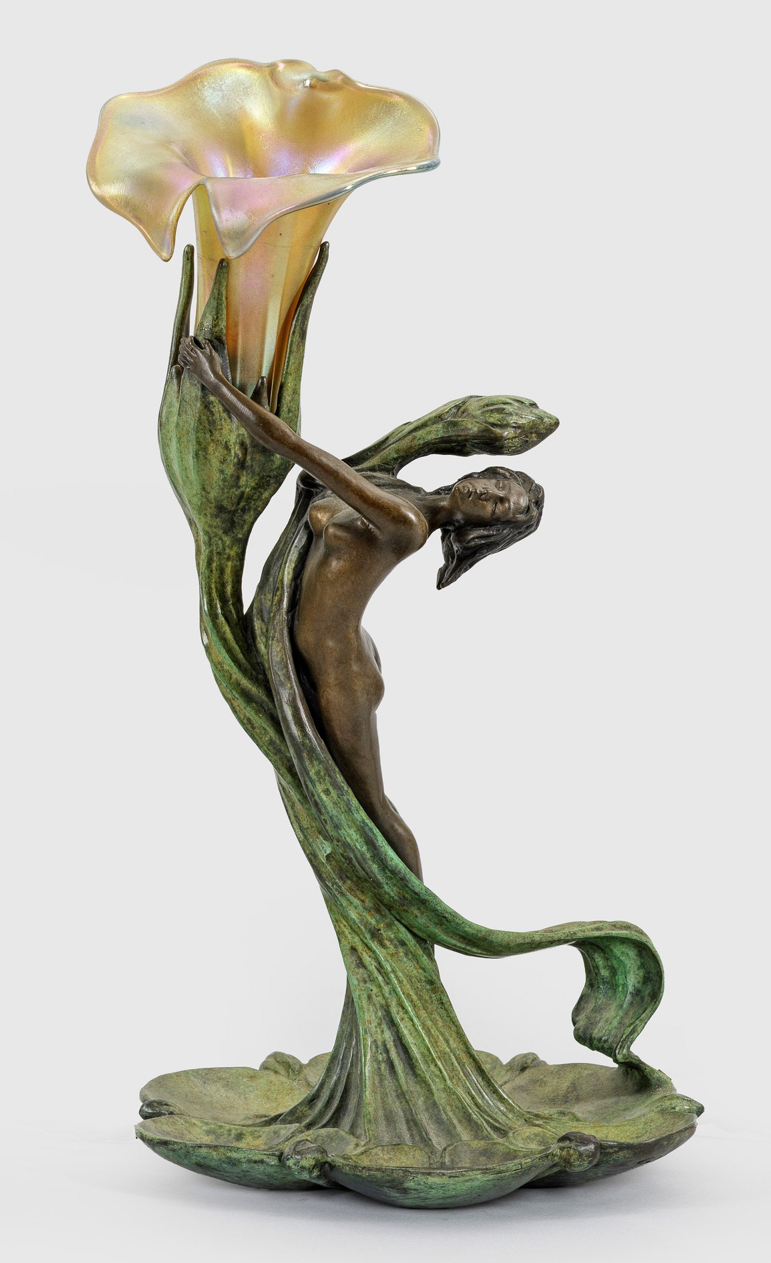 Jugendstil-Tischlampe: nach einem Entwurf von Gustav Gurschner 1-flg.; Bronze, dunkel bzw. hellgrün patiniert sowie irisierendes Glas. Über Basis aus Seerosenblättern stark geschwungener, vegetabil gestalteter Schaft mit