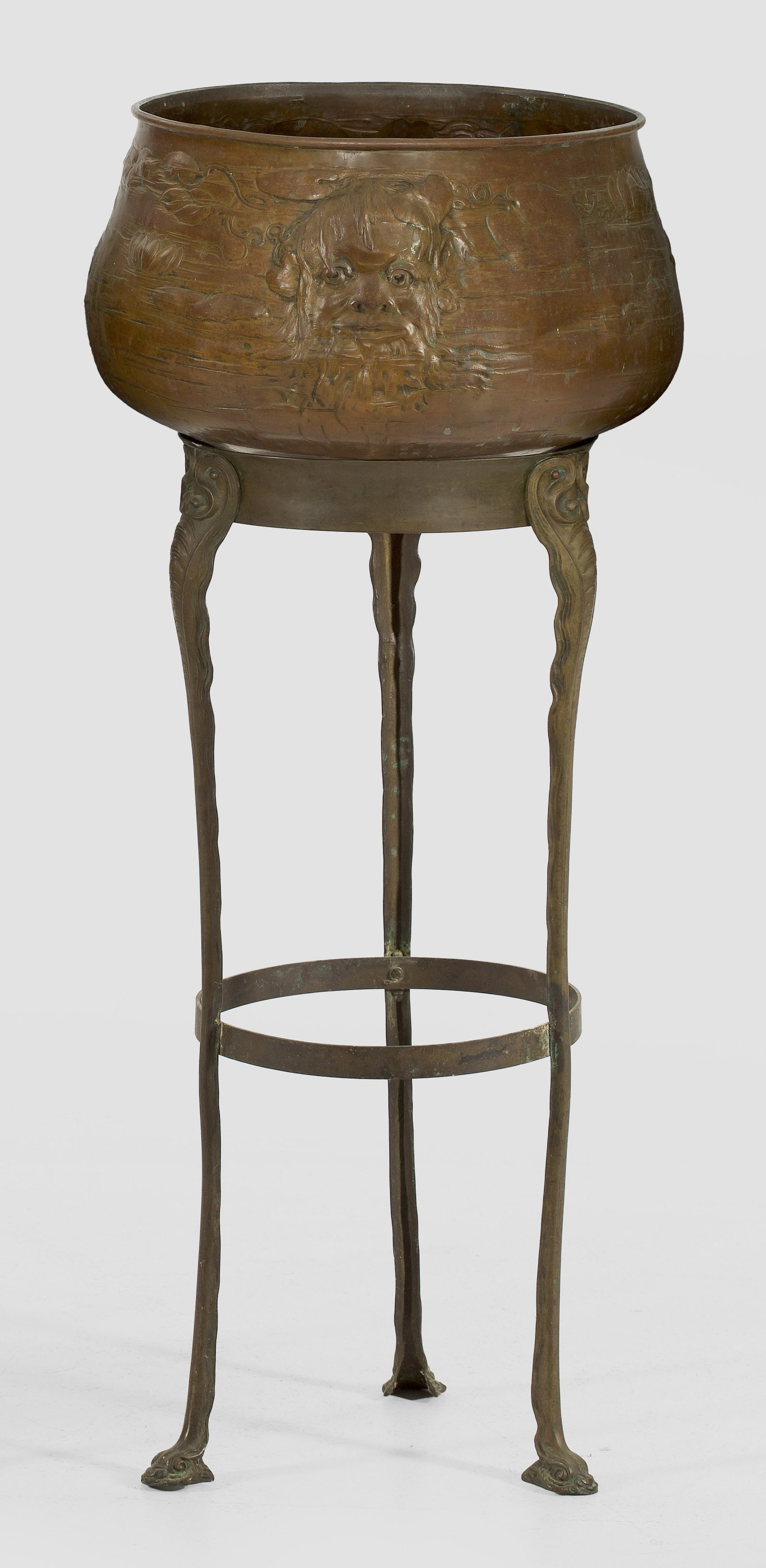 Jugendstil-Cachepot: Messing und Kupfer. Gestell aus bombierter, konkav eingezogener Zarge auf gestreckten, vegetabil gestalteten Beinen, in plastisch gestalteten Delfinköpfen endend. Oberhalb balusterförmiger Korpus mi