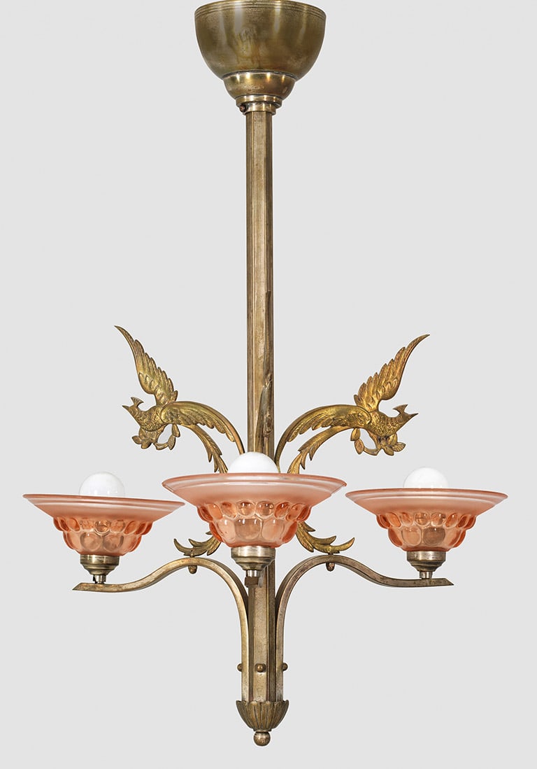 Kleine Art Déco-Deckenlampe: 3-flg.; Messing, mit Resten alter Vernickelung sowie roséfarbenes Glas. Schlanker, gekanteter Schaft. Davon ausgehend durchbrochen gearbeitete Leuchterarme mit Paradiesvögeln als Träger für flache