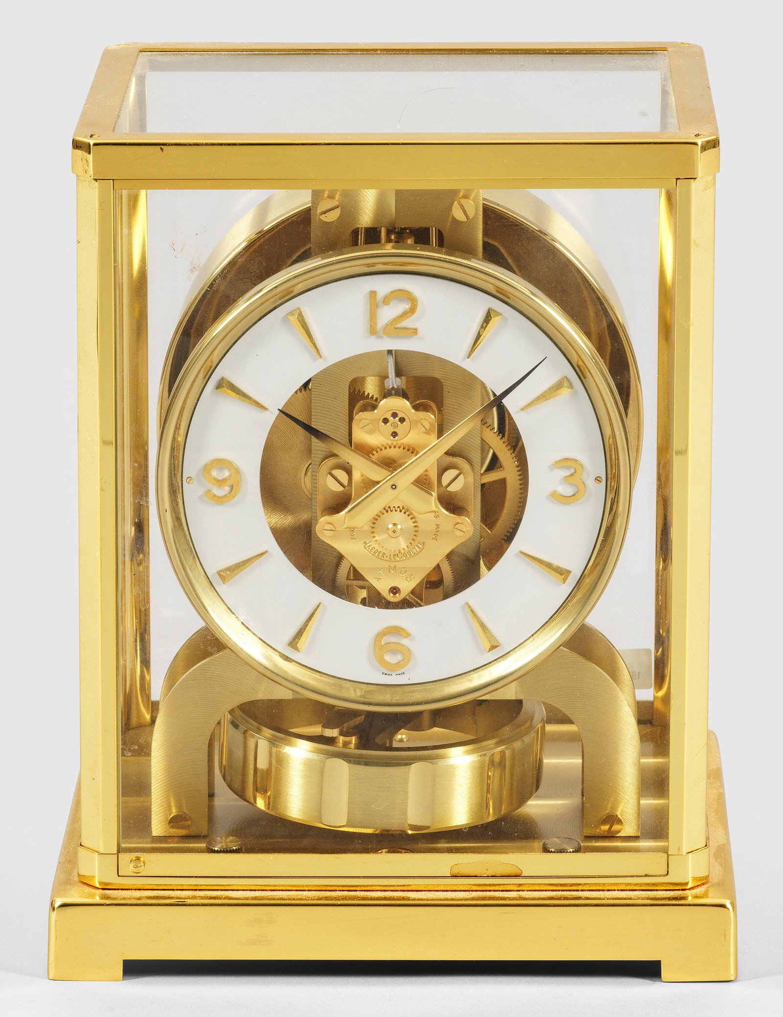 ATMOS-Tischuhr von Jaeger LeCoultre: sog. "Pendule Perpetuelle". Messing, vergoldet. Allseitig verglaster, rechteckiger Korpus. Profilgerahmter weißer Ziffernring mit Indexen und arabischen Zahlen. Bez. ATMOS, Jaeger LeCoultre. Rotation