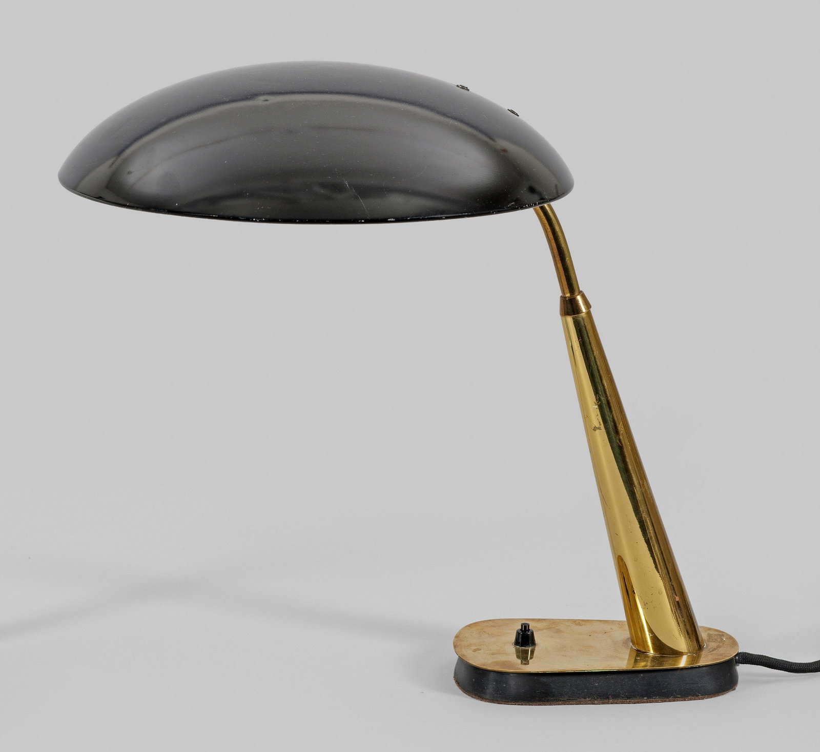 Schreibtischlampe von Christian Dell: Modell 6770. 1-flg.; Messing sowie schwarz lackiertes Metall. Über flacher Basis schräggestellter, sich konisch verjüngender Schaft als Träger für flach gewölbten, schwenkbaren Lampenschirm. Unb