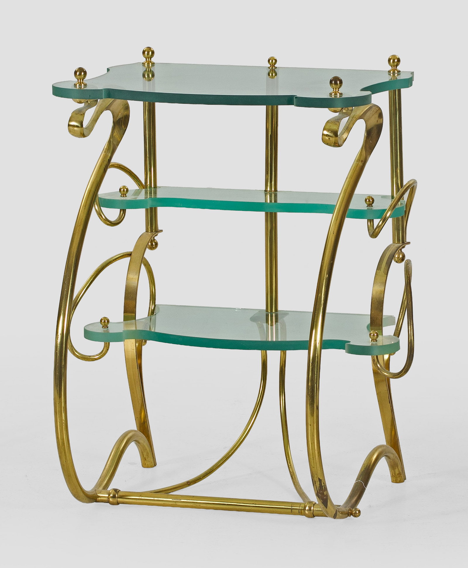 Dekorativer Beistelltisch im Jugendstil: Messing und farbloses Glas. Offen gestalteter Korpus aus stark geschwungenen, arabesk angelegten Volutenmotiven als Träger für passig geschweifte Deckplatte und korrespondierende Ablageflächen, tei
