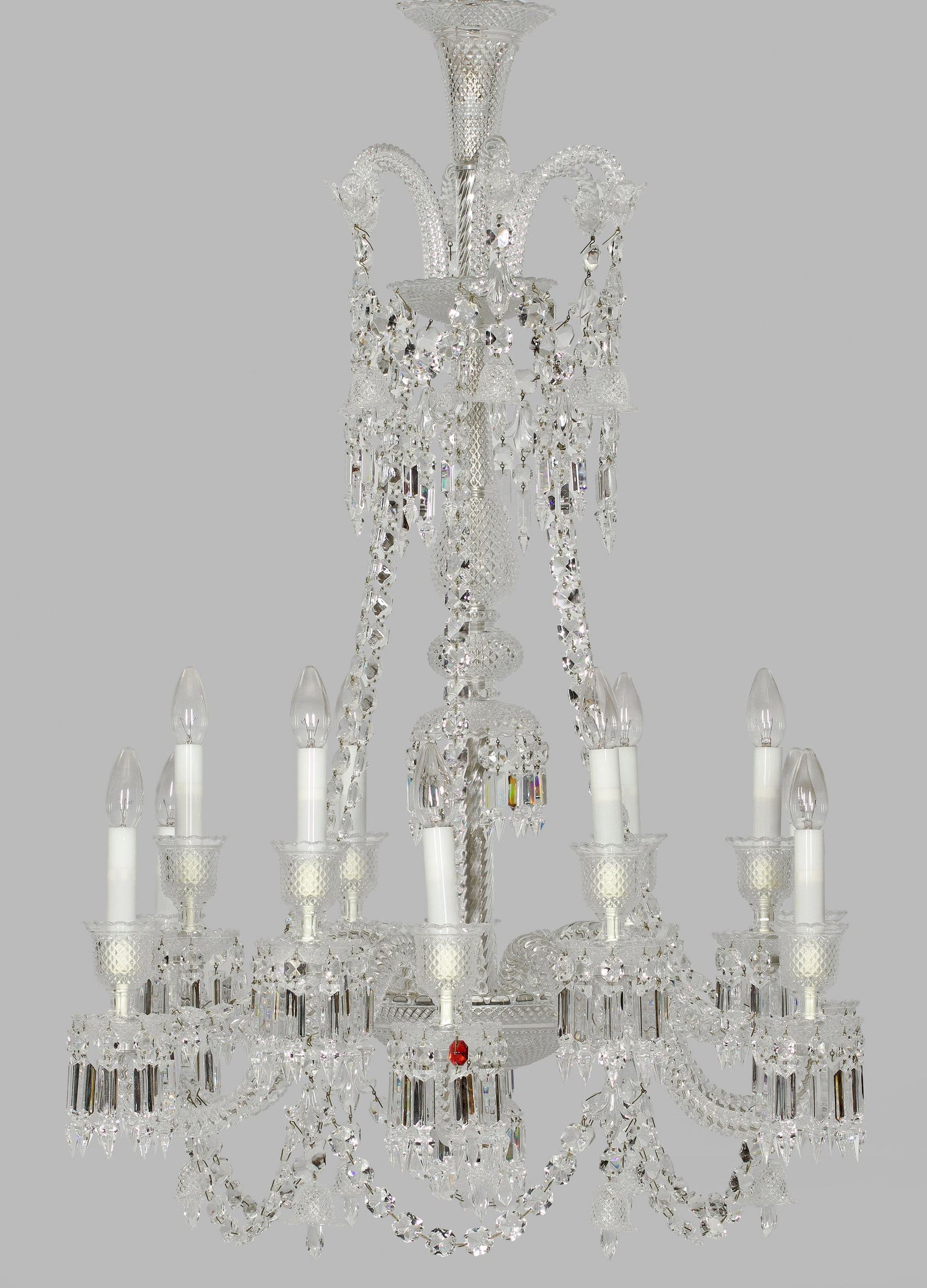 Luxuriöser Deckenlüster "Zénit" von Baccarat: 12-flg.; Farbloses Kristallglas. Mehrfach gegliederter Balusterschaft. Unterhalb davon ausgehend stark geschwungene, in sich gedrehte Leuchterarme als Träger für Leuchtmittel. Tief gemuldete Traufsc