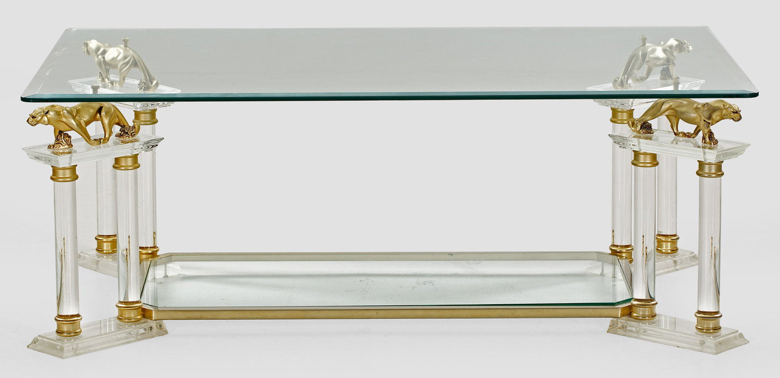 Extravaganter Couchtisch: Farbloses Acrylglas, Glas und Metall, vergoldet. Über flachen, schräggestellten Sockeln paarweise angeordnete Vollsäulen sowie schreitende Panther als Träger für facettierte Deckplatte. H. 47 cm.