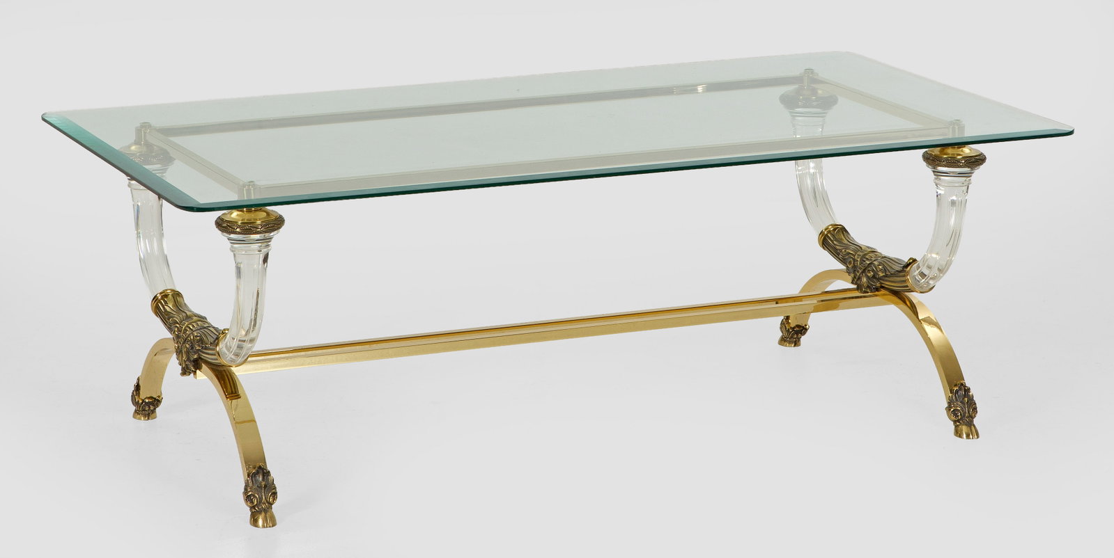 Dekorativer Couchtisch: Messing, vergoldet, Acrylglas und Glas. Gestell aus stark gebogten gekanteten bzw. kannelierten Streben, dazwischen durch schmale Stege verbunden. Quadratische, facettierte Deckplatte mit gerundeten E