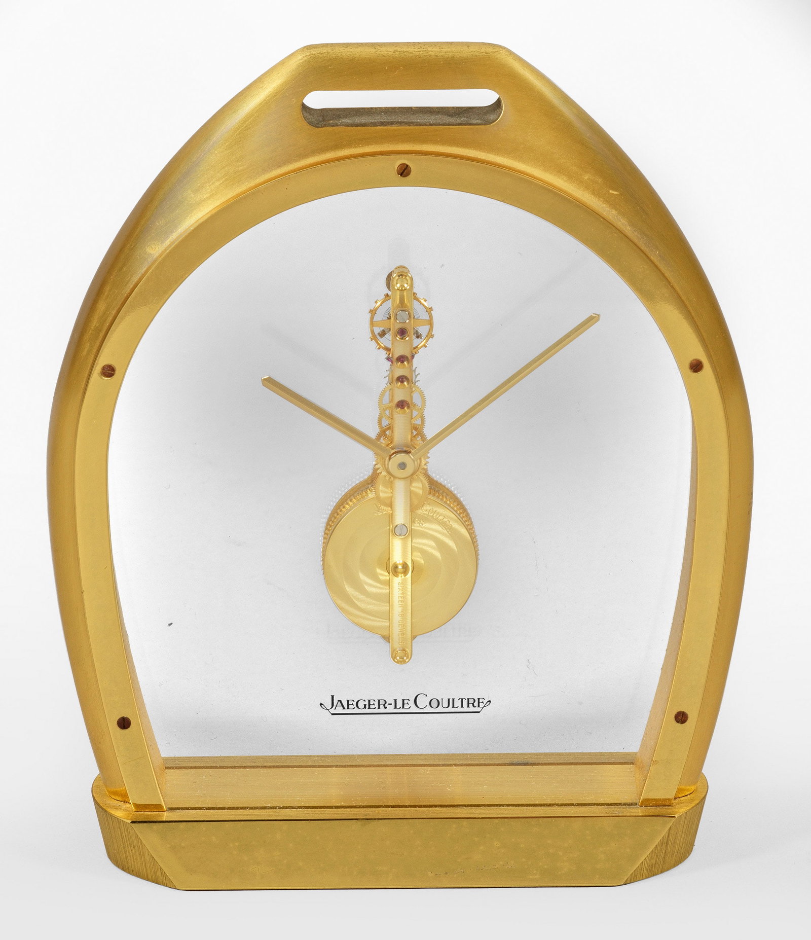 Tischuhr von Jaeger LeCoultre: Messing, vergoldet. Bombiertes, beidseitig transparentes Gehäuse in Form eines stilisierten Hufeisens auf flacher Basis. Skelettiertes Stabwerk mit Ankerhemmung und Handaufzug. Front bez. Jaeger LeCo