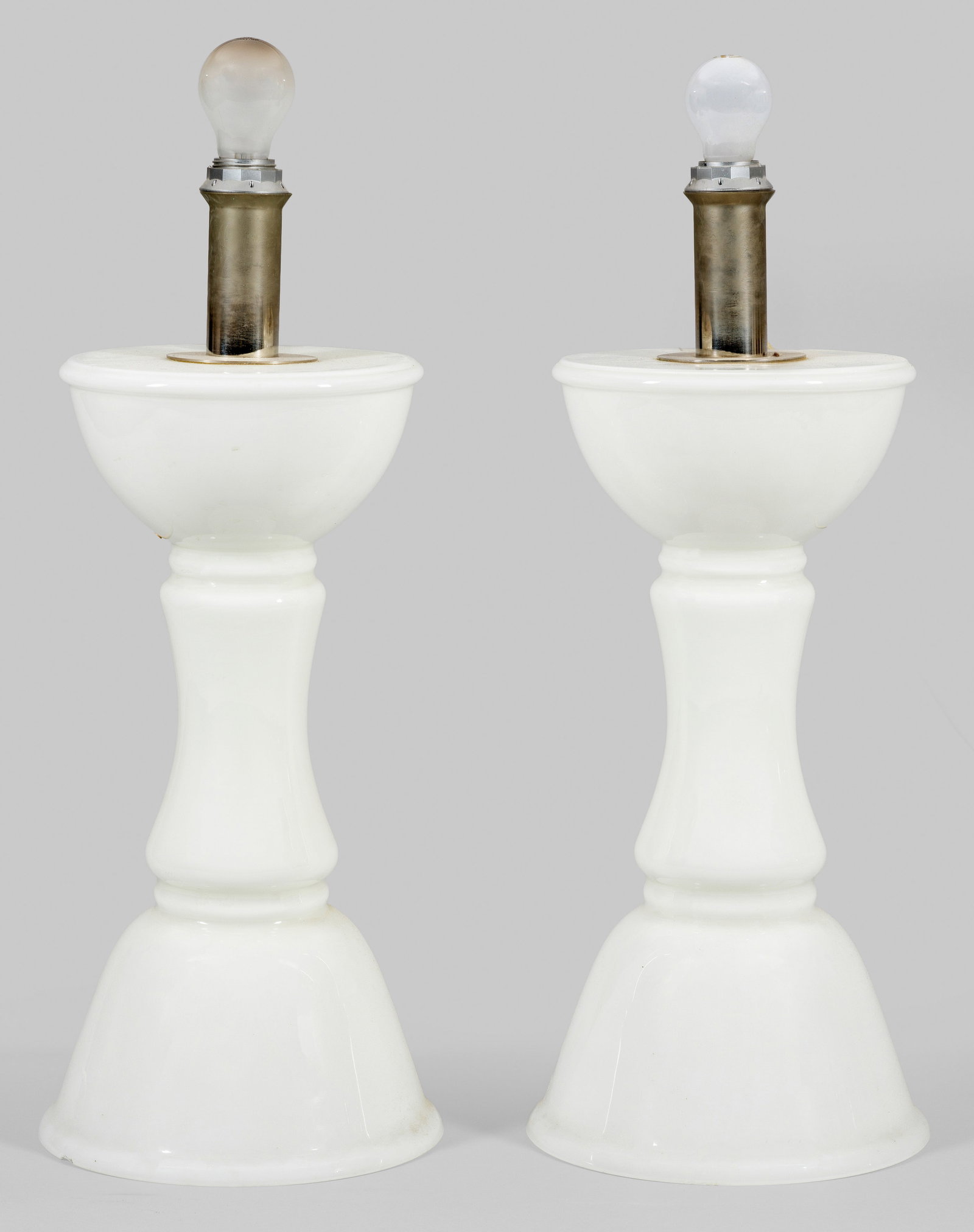 Paar große Tischlampen von Ingo Maurer: 1-flg. Weißes Glas und silberfarbenes Metall. Balusterförmiger Korpus mit glockenförmiger Basis als Träger für Leuchtmittel. Ohne Lampenschirm. Unbez.; Unw. best.; Elektrifiziert. Entw. Ingo Maur