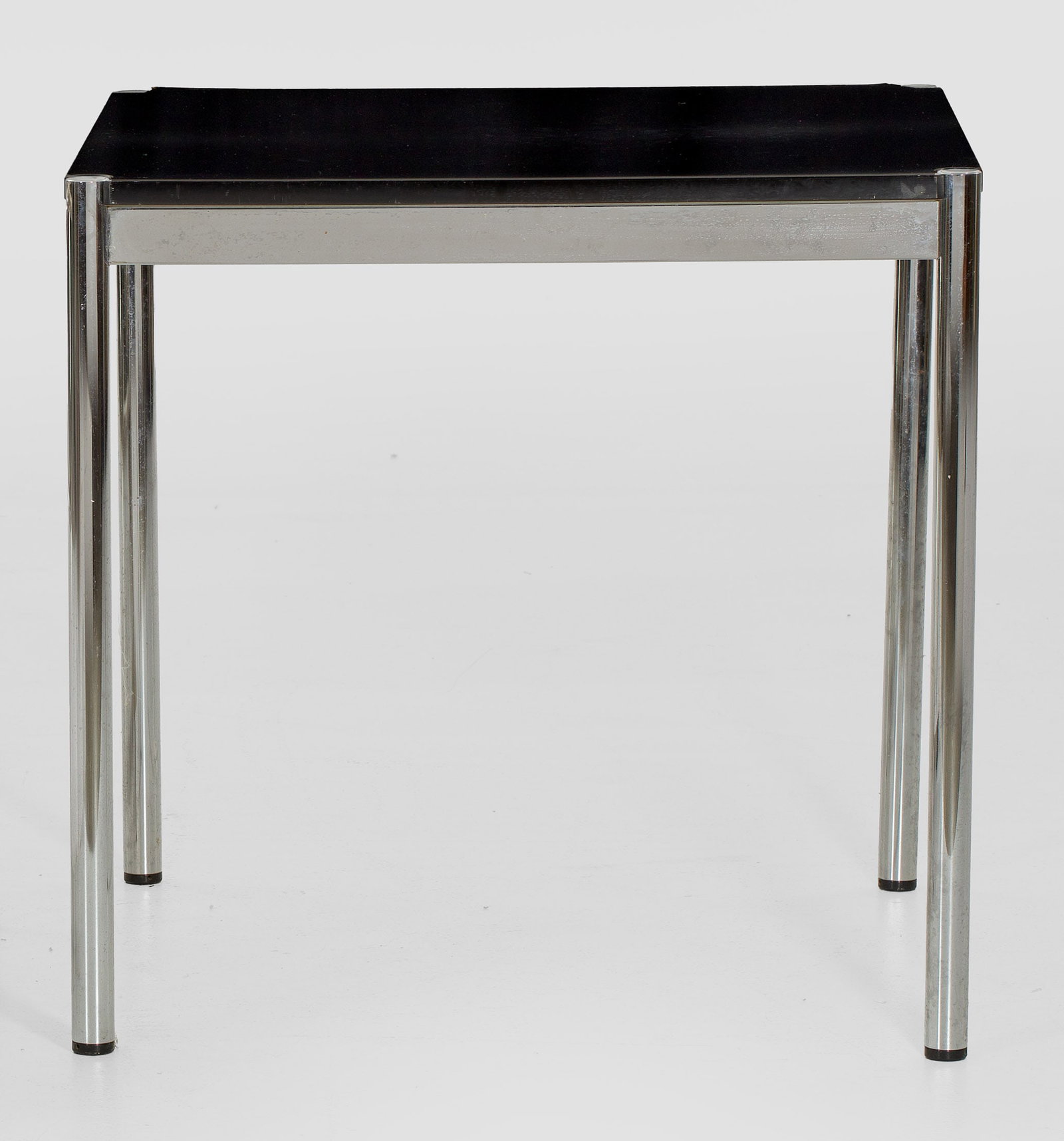 Tisch von USM Haller: Verchromtes Metall sowie schwarz beschichtetes Holz. Kräftige Rundstäbe als Stützen für gerade, rechteckige Zarge und entsprechende Deckplatte. H. 74 cm. 75 cm x 75 cm. A chromed metal table by US