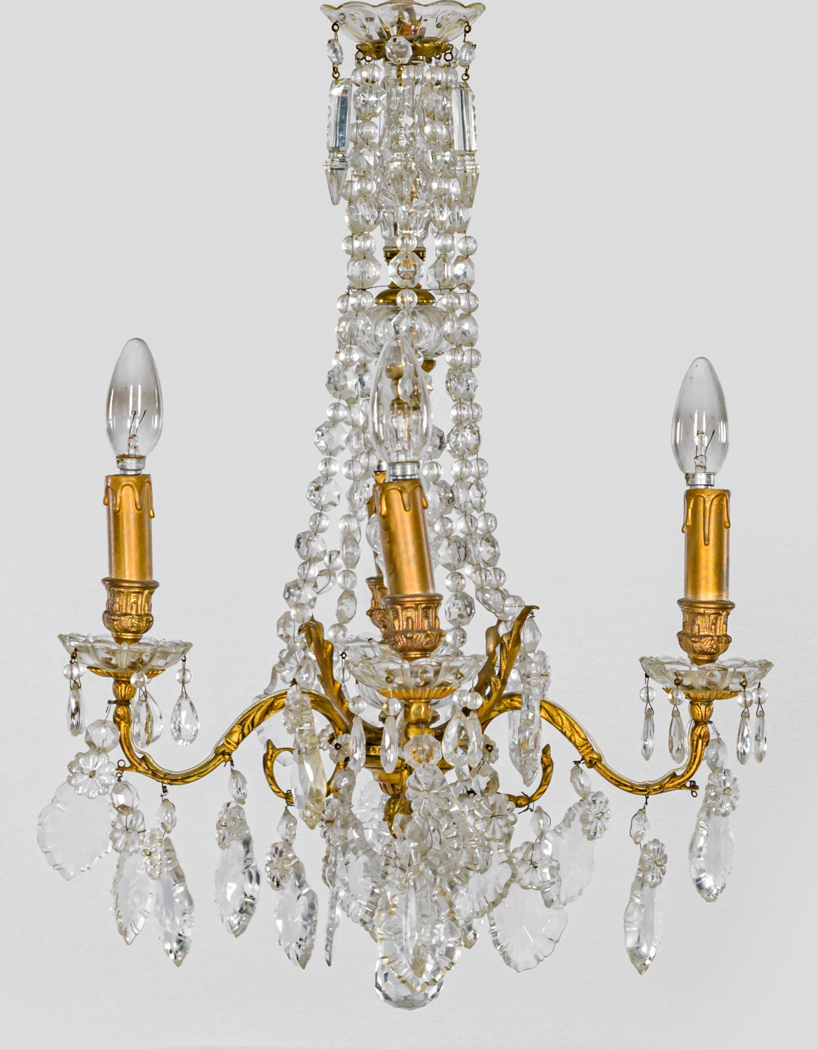 Kleiner Belle Epoque-Deckenlüster: 4-flg.; Messing und farbloses Glas. Mehrfach gegliederter Balusterschaft. Unterhalb davon ausgehend stark geschwungene Leuchterarme aus eingerollten Voluten als Träger für Leuchtmittel. Reicher Beha