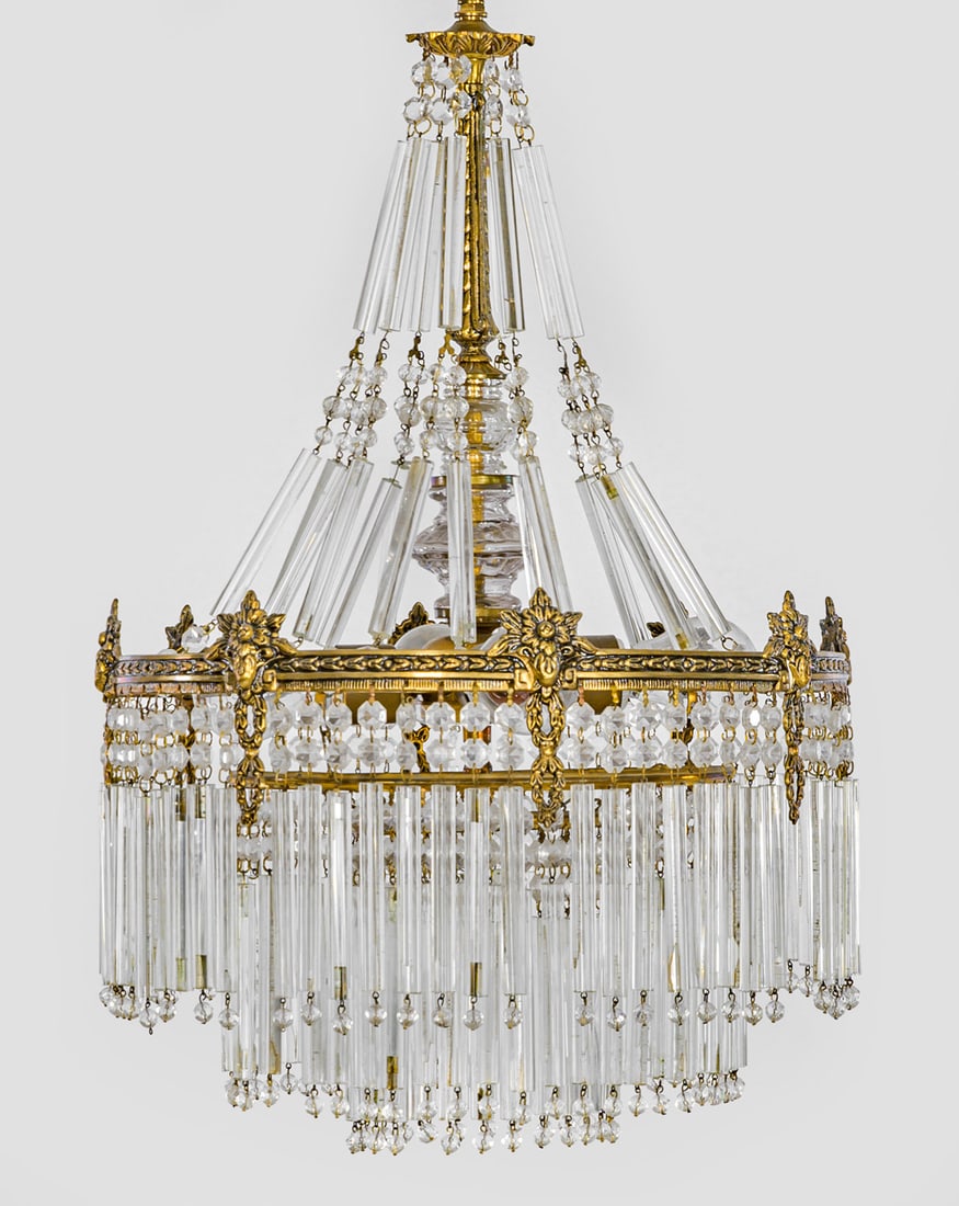 Napoleon III-Deckenlampe: Messing, patiniert und farbloses Glas. Ornamentierter Reif mit reichem Behang aus langen, gestuft angeordneten Stäben, in der Mitte vier Lampenfassungen. Oberhalb gegliederter Balusterschaft. Elektri
