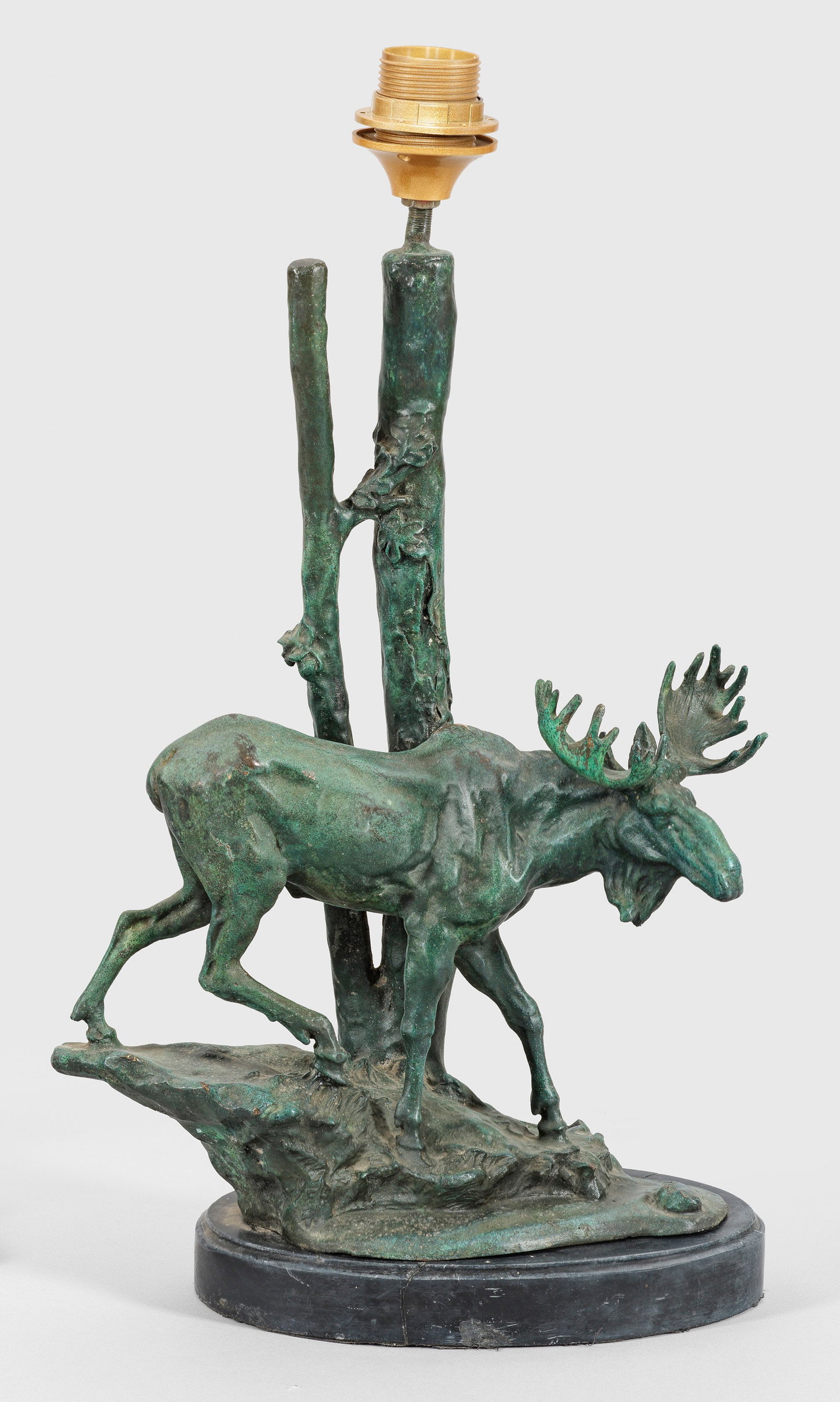 Skulpturale Tischlampe: 1-flg.; Bronze, grün patiniert und schwarzer Marmor. Über ovaler, besch. Plinthe vollplastische Darstellung eines Elchs auf naturalistisch gestalteter Basis. Dahinter schlanker Schaft in Form eines 