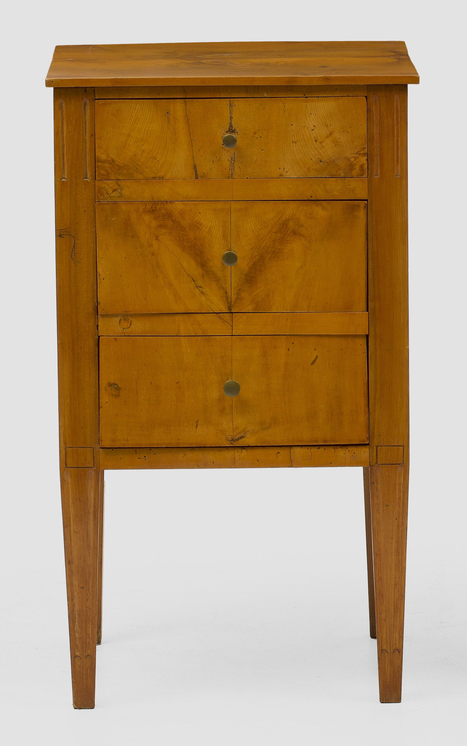 Biedermeier-Pfeilerkommode: Birkenholz, furniert. Gerader, hochrechteckig angelegter Korpus auf konischen Vierkantbeinen. In der gegliederten Front drei Schubladen. Gering überstehende Deckplatte. Erg.; H. 75 cm. 43,5 cm x 39,5
