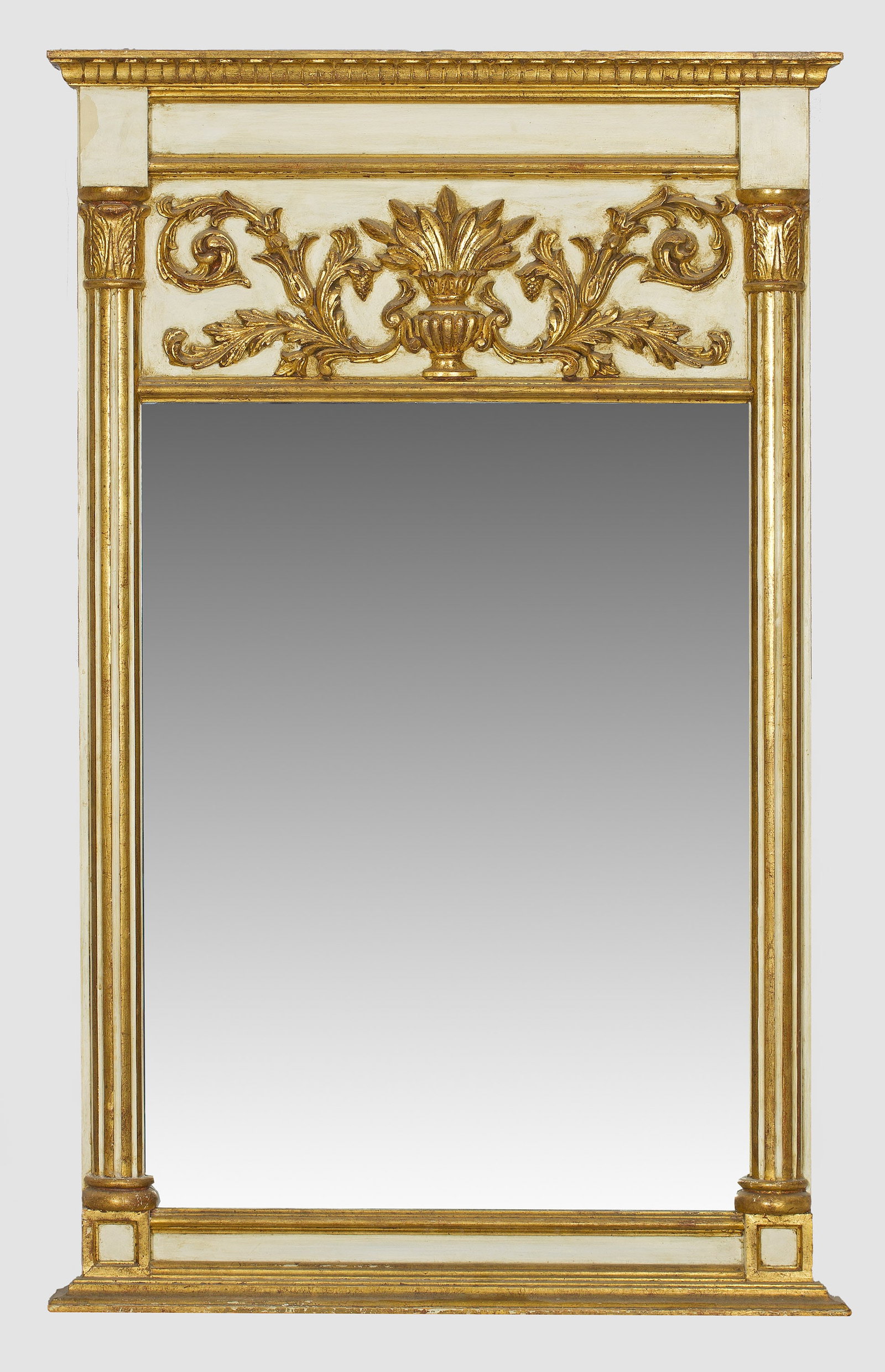 Wandspiegel im Louis XVI-Stil: Holz und Surrogat, elfenbeinfarben gefasst und teilw. vergoldet. Gerade, hochrechteckige Spiegelrahmung, flankiert von kannelierten Halbsäulen. Im breiten Giebelfeld zentrales Vasenmotiv sowie erhabe