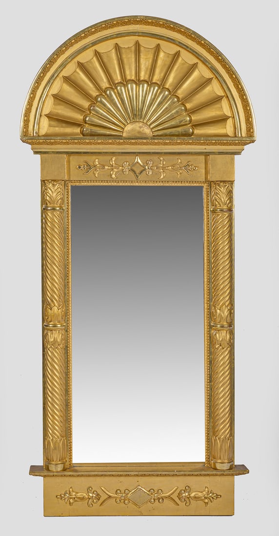 Gustavianischer Wandspiegel: Holz, geschnitzt, gefasst und vergoldet. Gerade, hochrechteckige Spiegelrahmung, flankiert von eingestellten Baluster-Halbsäulen. Oberhalb breites Gesims sowie Segmentgiebel mit stilisiertem Sonnenmo