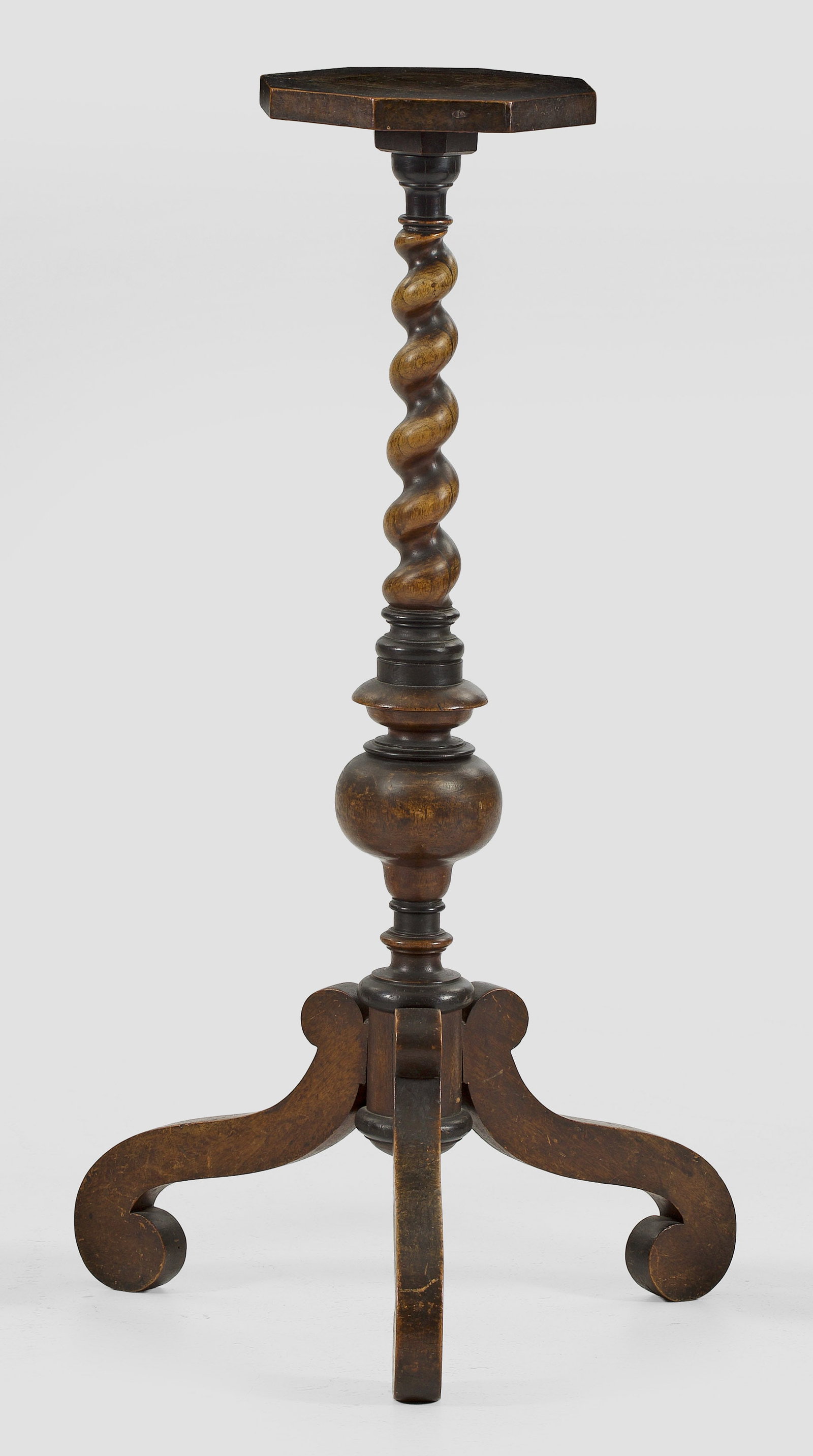 Barock-Torchére: Nussbaum. Mehrfach gegliederter, teilw. in sich gedrehter Schaft auf gegeneinander gestellten Volutenbeinen als Träger für kleine oktogonale Deckplatte. H. 92,5 cm. A South German walnut Baroque sta