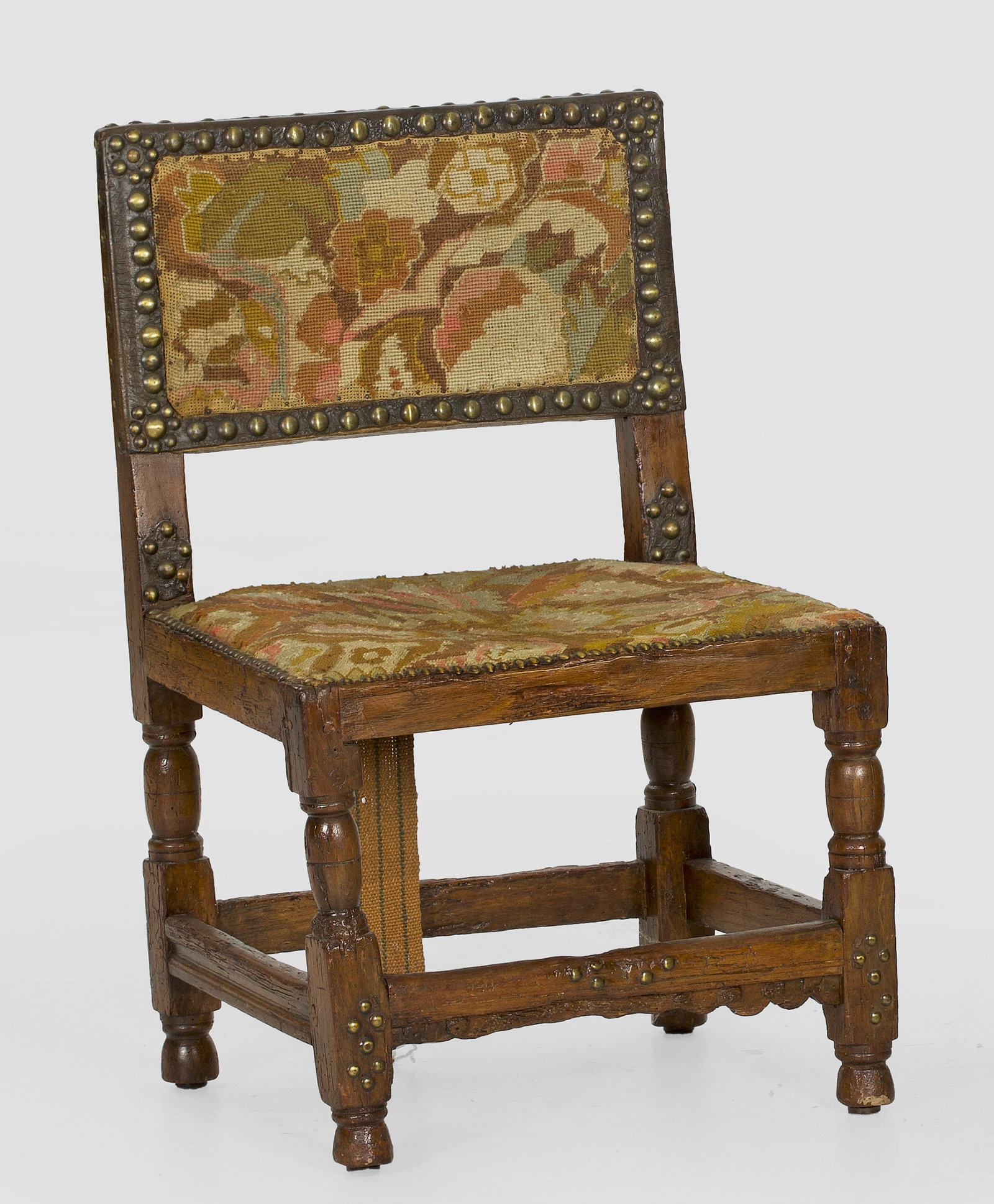 Barock-Kinderstuhl: Nussbaum. Gerade Zarge auf niedrigen Balusterbeinen, durch schmale Stege verbunden. Rechteckige Rückenlehne. Sitz- und Lehnenfläche mit Gobelinbezug. Altersspuren. H. 71 cm. 45 cm x 38,5 cm. Sitz-H.