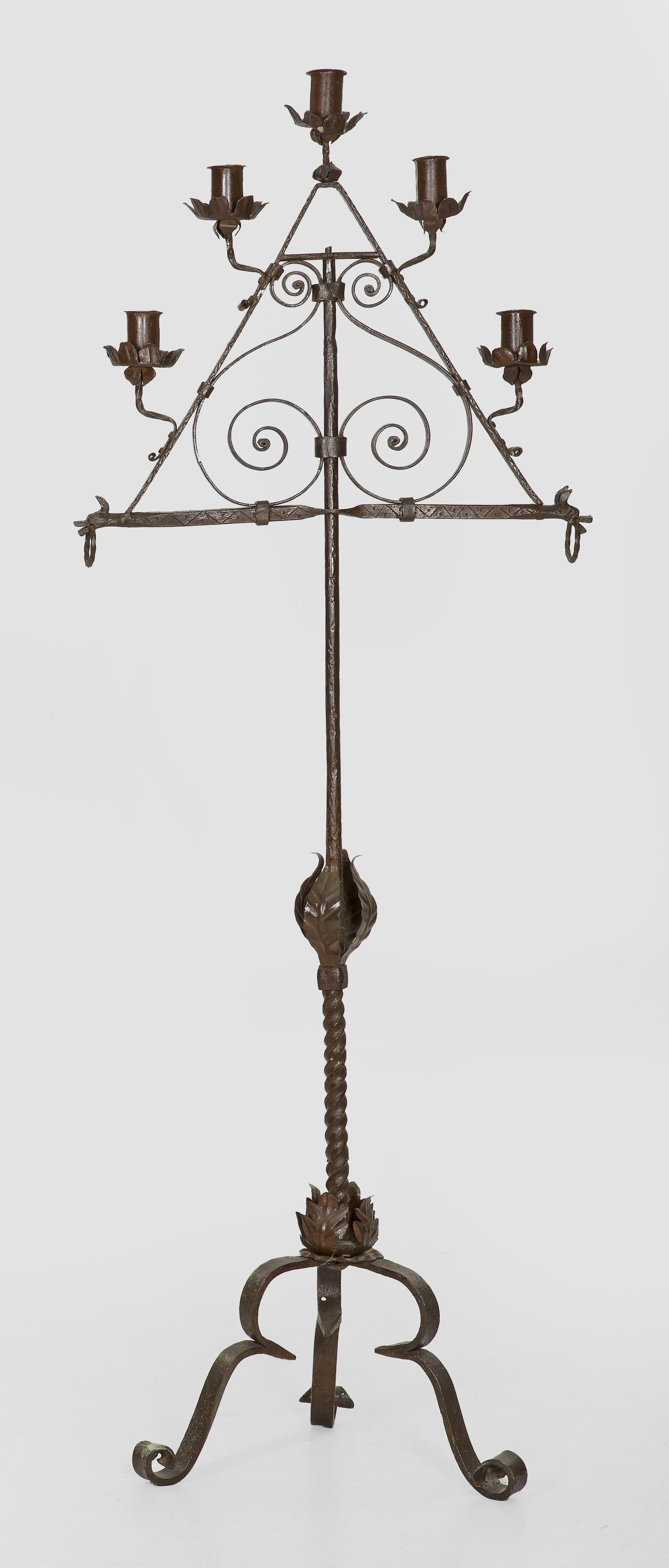 Hallenleuchter im Barock-Stil: 5-flg.; Schmiedeeisen und Metall. Sich konisch verjüngender, teilw. in sich gedrehter Schaft auf Volutenbeinen. Oberhalb dreieckig angelegtes Leuchterelement mit zylinderförmigen Tüllen. H. 164 cm.