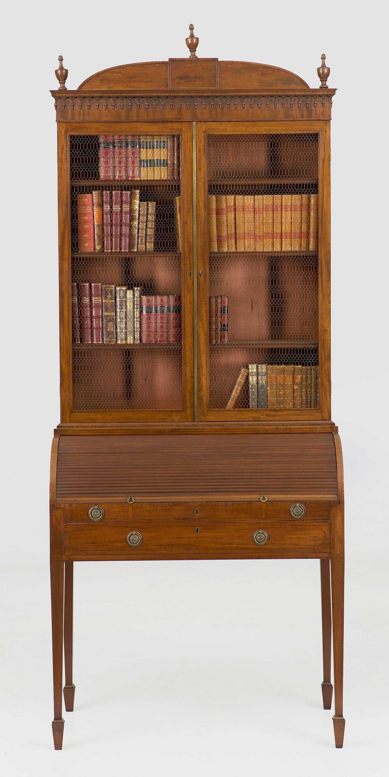 Sheraton Secretaire Bookcase mit Rolloverschluss: Mahagoni. Gerader Zargenkasten auf hohen, konischen Vierkantbeinen. In der gegliederten Front breites Schubfach sowie bombierter Rolloverschluss und ausziehbare Arbeitsfläche mit pultartig