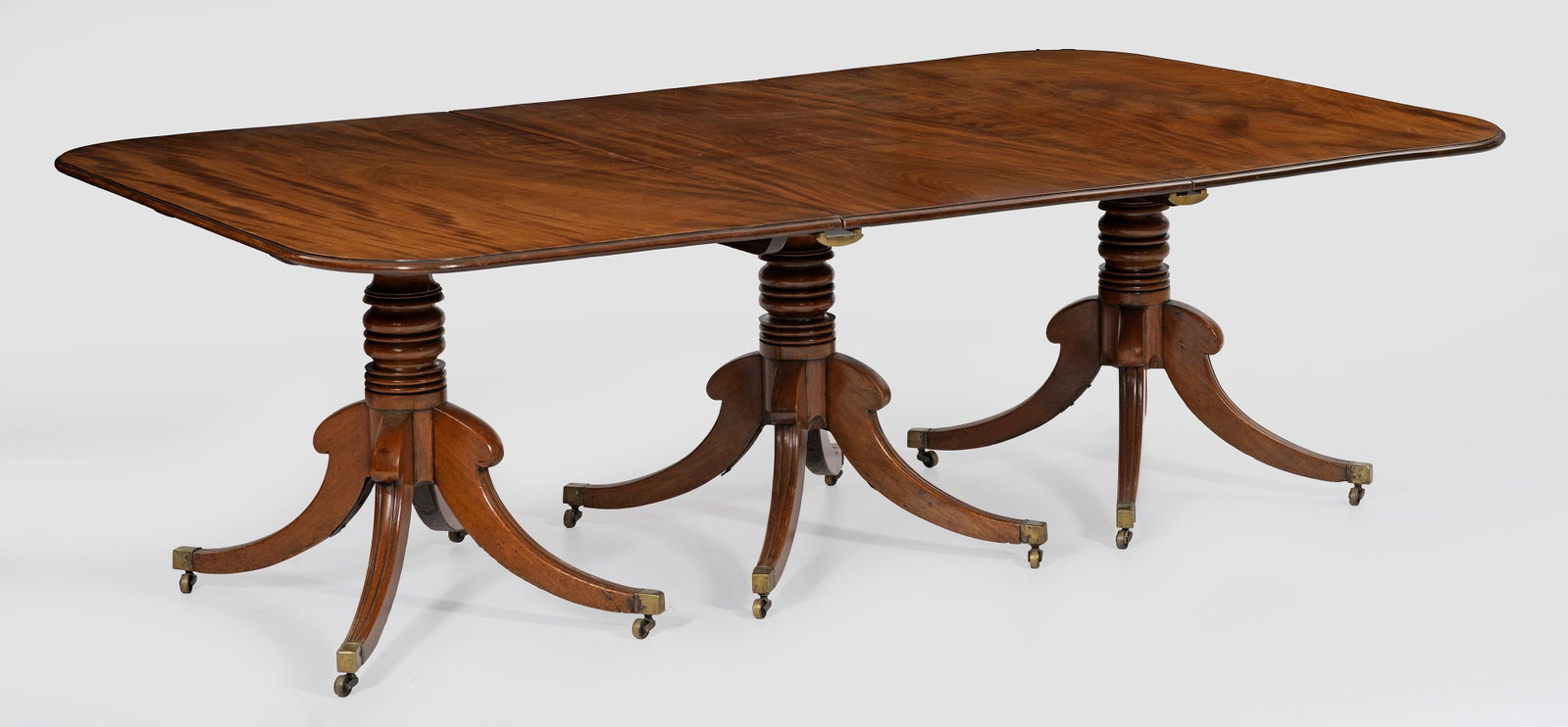 Viktorianischer Dining Table: Mahagoni. Kräftiger, mehrfach gegliederter Balusterschaft auf volutenähnlich ausgestellten Beinen mit Messingrollen. Profilierte Deckplatte mit gerundeten Ecken. Zwei Einsteckplatten. H. 71 cm. 136 