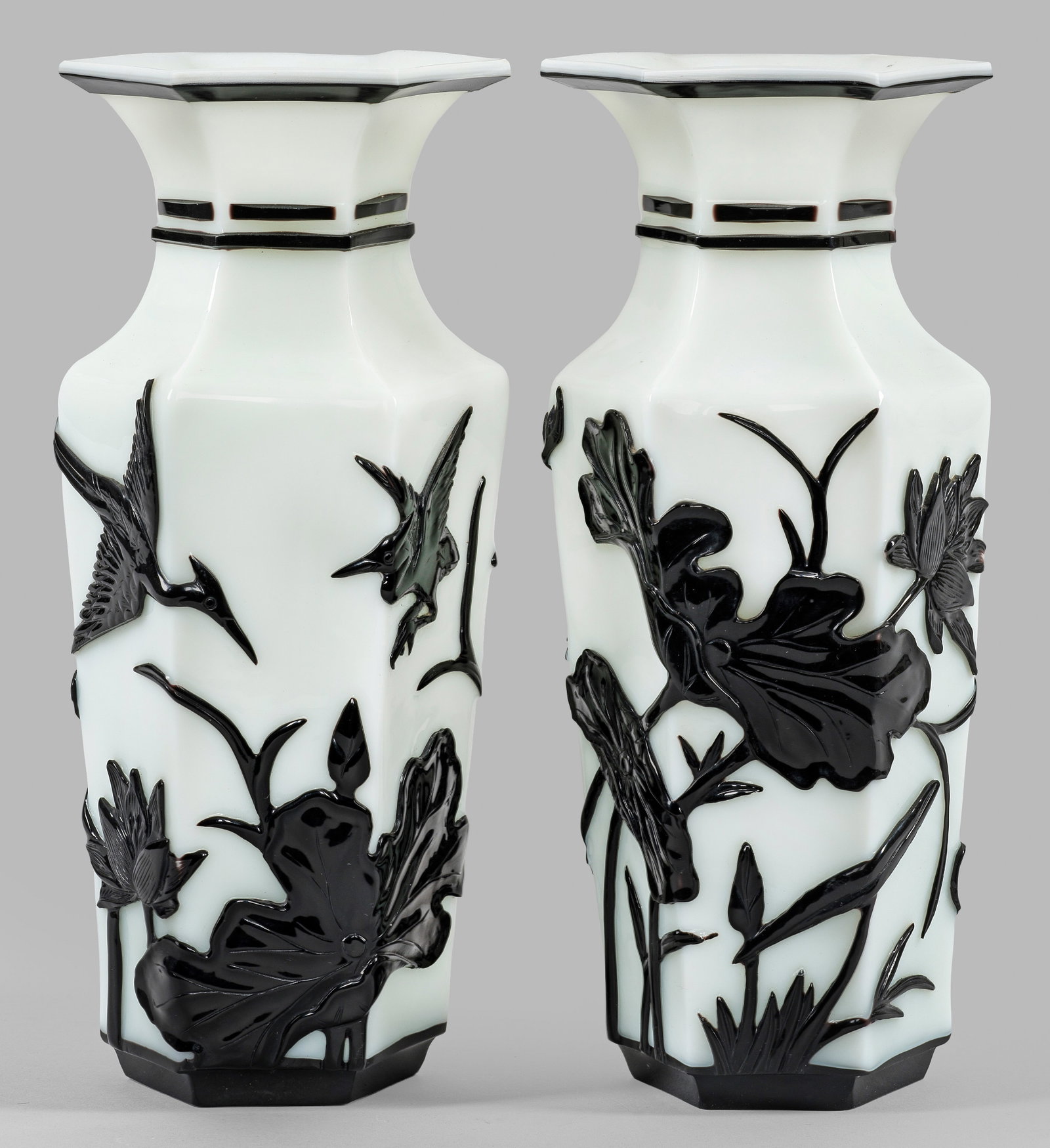 Paar "Pekingglas"-Vasen: Milchglas, schwarz überfangen. Sechseckige Balusterform. Auf der Wandung umlaufender Dekor aus stilisierter Gartenlandschaft mit Lotusblumen und Reihern. H. 26 cm. A pair of Chinese black and white