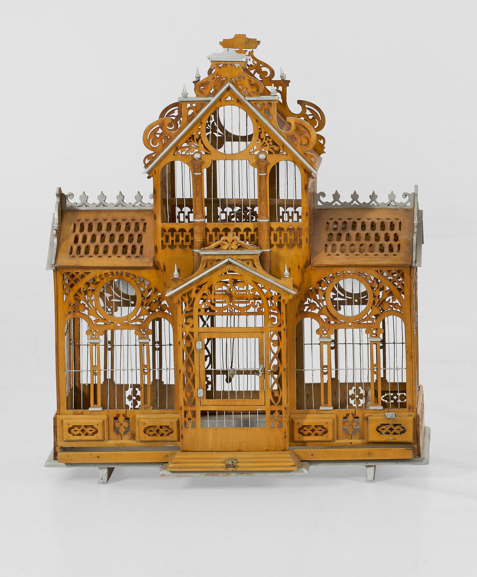 Viktorianischer Vogelkäfig: Holz, teilw. silberfarben bemalt. Offen gestalteter, architektonisch gegliederter Korpus aus stilisierten Säulen und gitterartig durchbrochenen Paneelen. Schmale Stäbe aus Metall. H. 73,5 cm. 62 cm