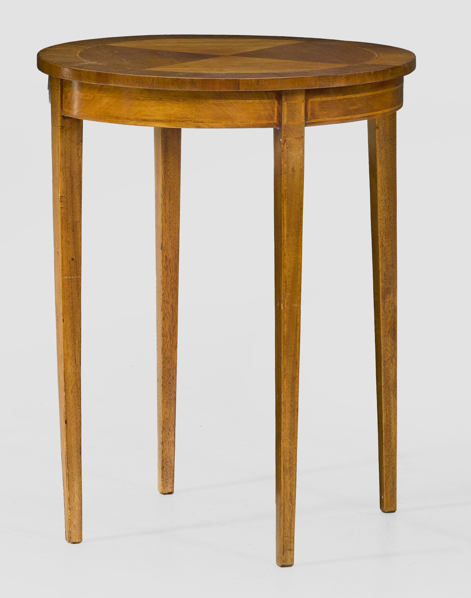 Beistelltisch: Mahagoni, furniert. Bombierte Zarge auf hohen, konischen Vierkantbeinen als Träger für runde Deckplatte. Flächendeckende Furnierfelder, von Bandeinlagen begrenzt. H. 69 cm. D. 55 cm. A mahogany sid