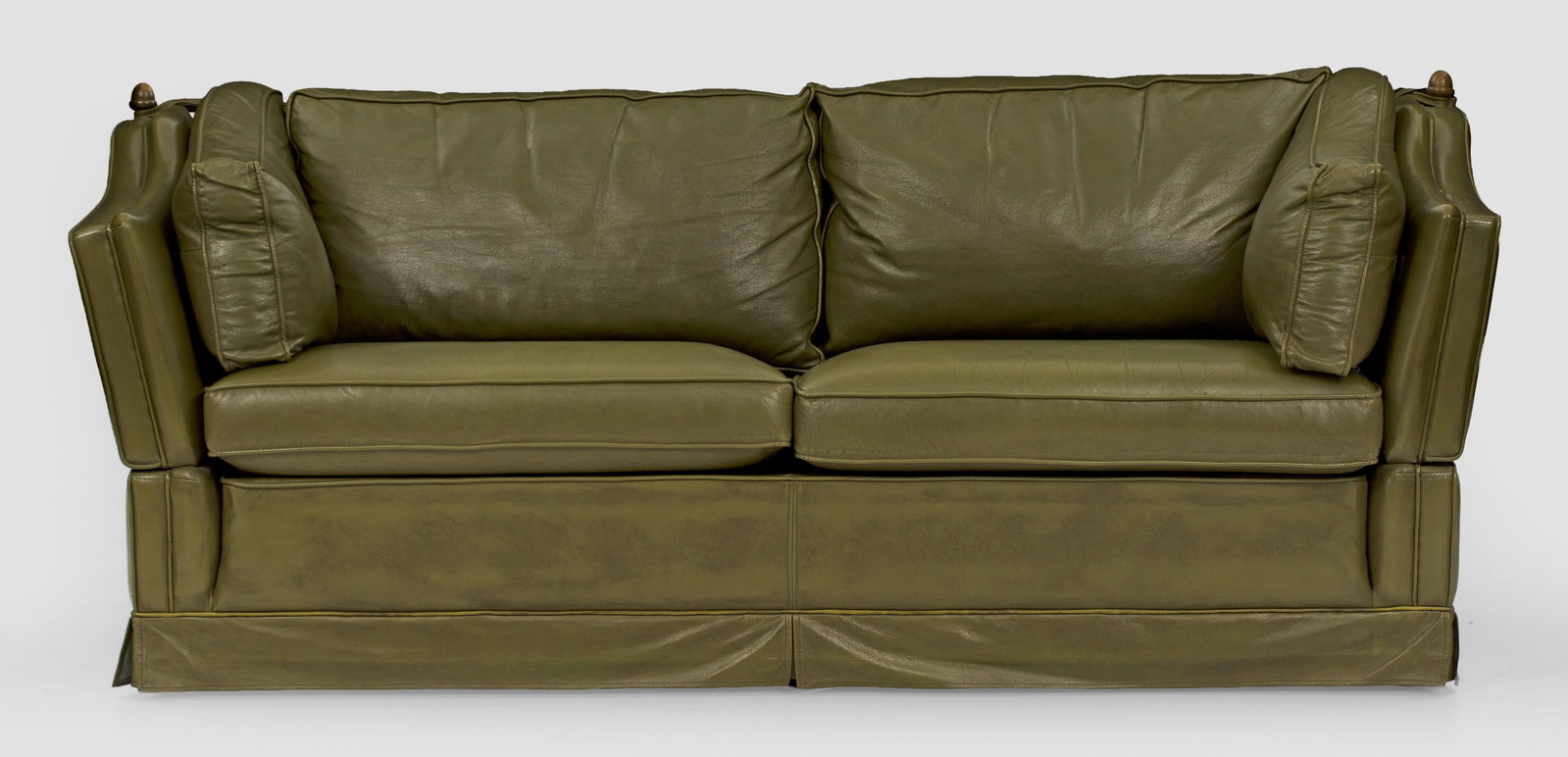 Klassisches Sofa: Grünes Leder. Gerader Korpus mit schräggestellter Rückenlehne mit Zapfenbekrönungen aus Messing sowie korrespondierenden, abklappbaren Armlehnen. Allseitig gepolstert und bezogen. H. 83 cm. 205 cm