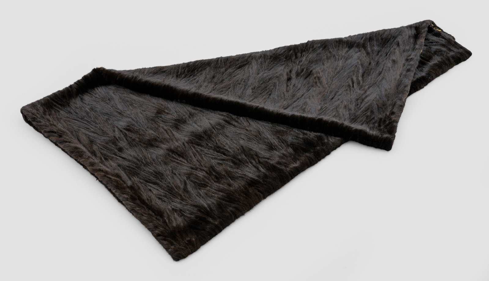 Pelzdecke: Rechteckige Decke aus dunkelbraunem, in schmalen Bahnen gegenläufig angelegtem Nerz in ausgelassener Verarbeitung. Rückseite aus extravagant gemustertem Stoff. 135 cm x 168 cm. A brown mink fur plai