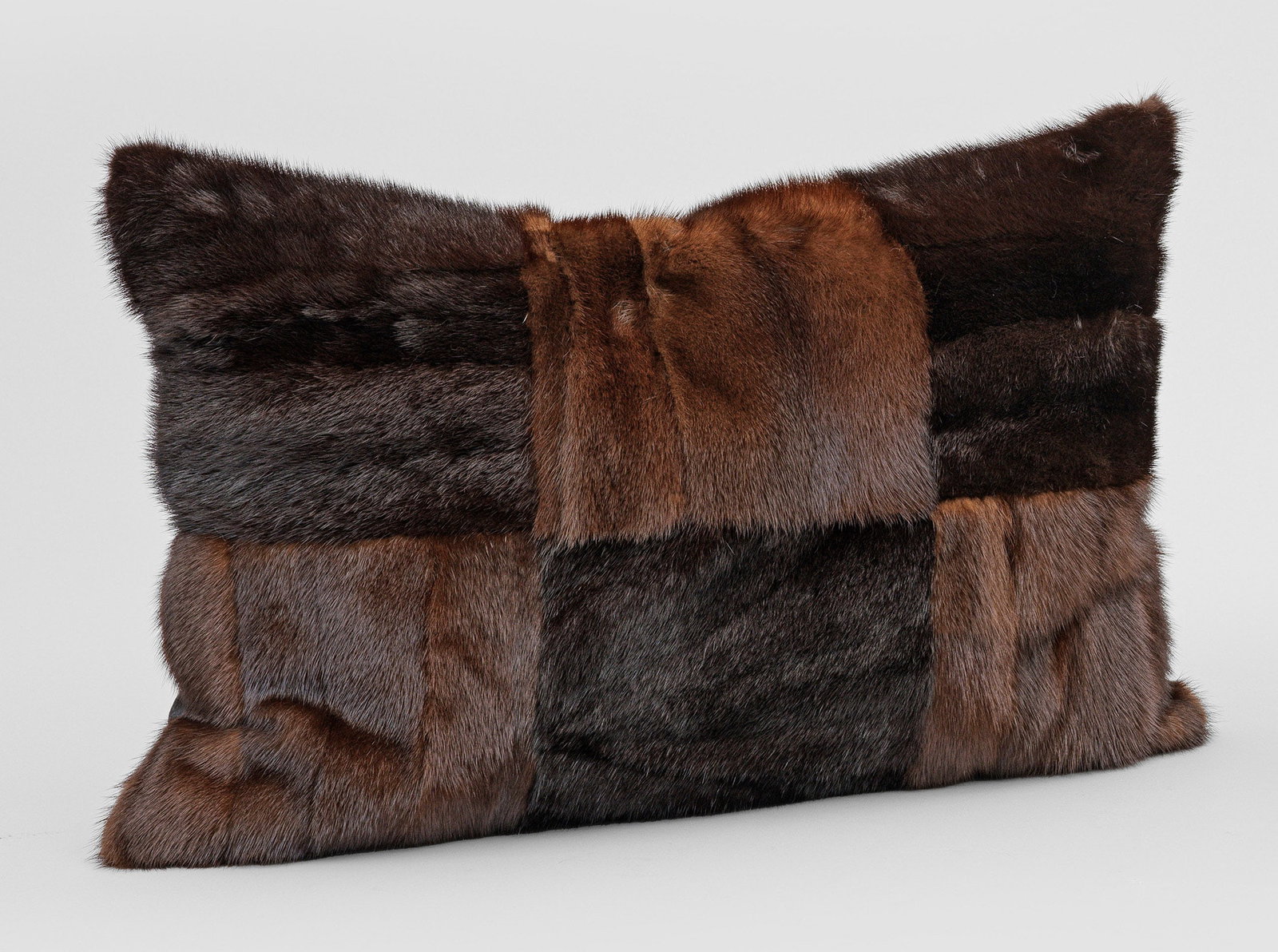 Pelzkissen: Rechteckiges Kissen aus braunem und dunkelbraunem, in Schachbrettmuster angeordnetem Nerz in ausgelassener Verarbeitung. Rückseite aus dunkelgrauem Woll-Cashmere. Inlett. Ca. 39 cm x 58 cm. A mink fu