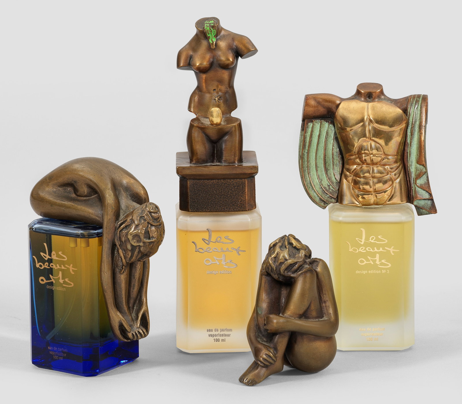 Drei Parfumflakons mit erotischer Bekrönung und Akt: aus der "Les beaux arts design edition" 4-tlg.; Bronze, braun und grün patiniert bzw. vergoldetes Metall und Glas. Auf hochrechteckig gekantetem Korpus abnehmbare Deckel in erotischer Gestalt. "Eros"