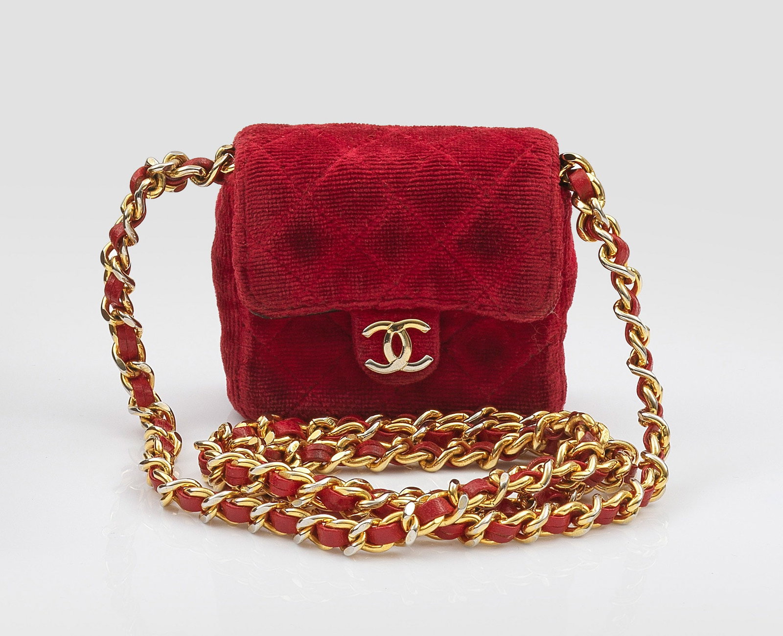 Kleine "Timeless Flap Bag" von CHANEL: Roter Samt in charakteristischer Rautensteppung und vergoldete Hardware. Rechteckiger Korpus mit CC-Logo und Steckverschluck. Innenfach aus schwarzem Leder, mit rotem Lederriemen durchzogene Gliederke