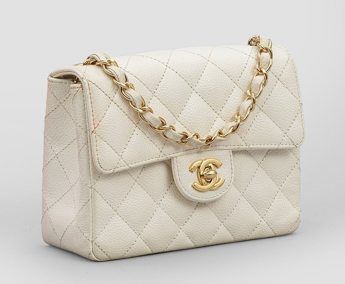"Timeless Flap Bag" von CHANEL: Cremefarbenes Caviarleder in charakteristischer Rautensteppung und vergoldete Hardware. Rechteckiger leicht konischer Korpus mit CC-Logo Drehverschluss. Innenfach mit zwei Seitenfächern sowie variabl