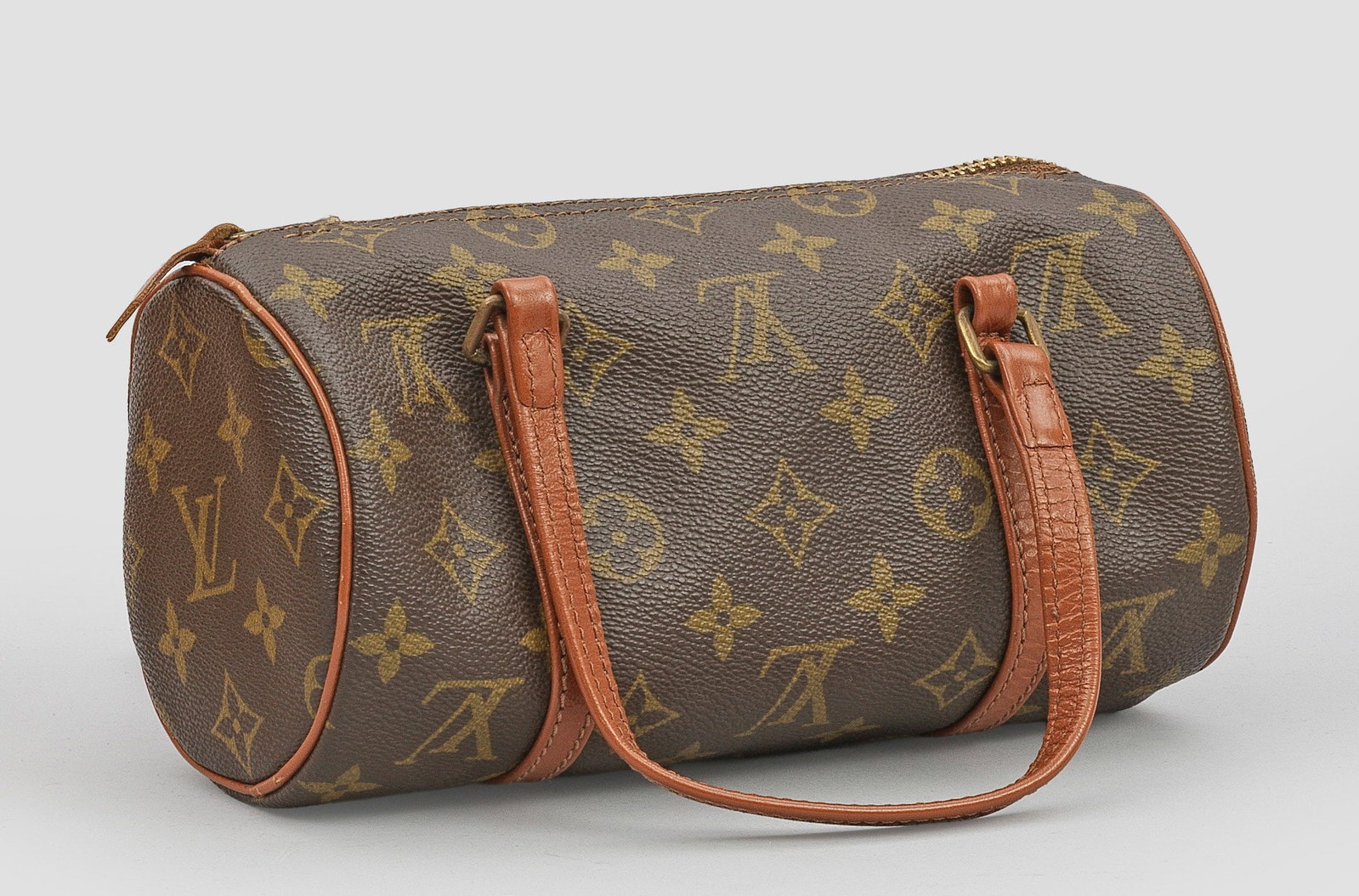 Kleine Vintage-Tasche "Papillon" von LOUIS VUITTON: Monogram-Canvas sowie Leder mit braunen Nähten. Walzenförmiger Korpus mit zwei Henkeln und Reißverschluss. Gebrauchsspuren. Herstellerzeichen. Date-Code 823. H. 11,5 cm. 10,5 cm x 22 cm A Vintage b