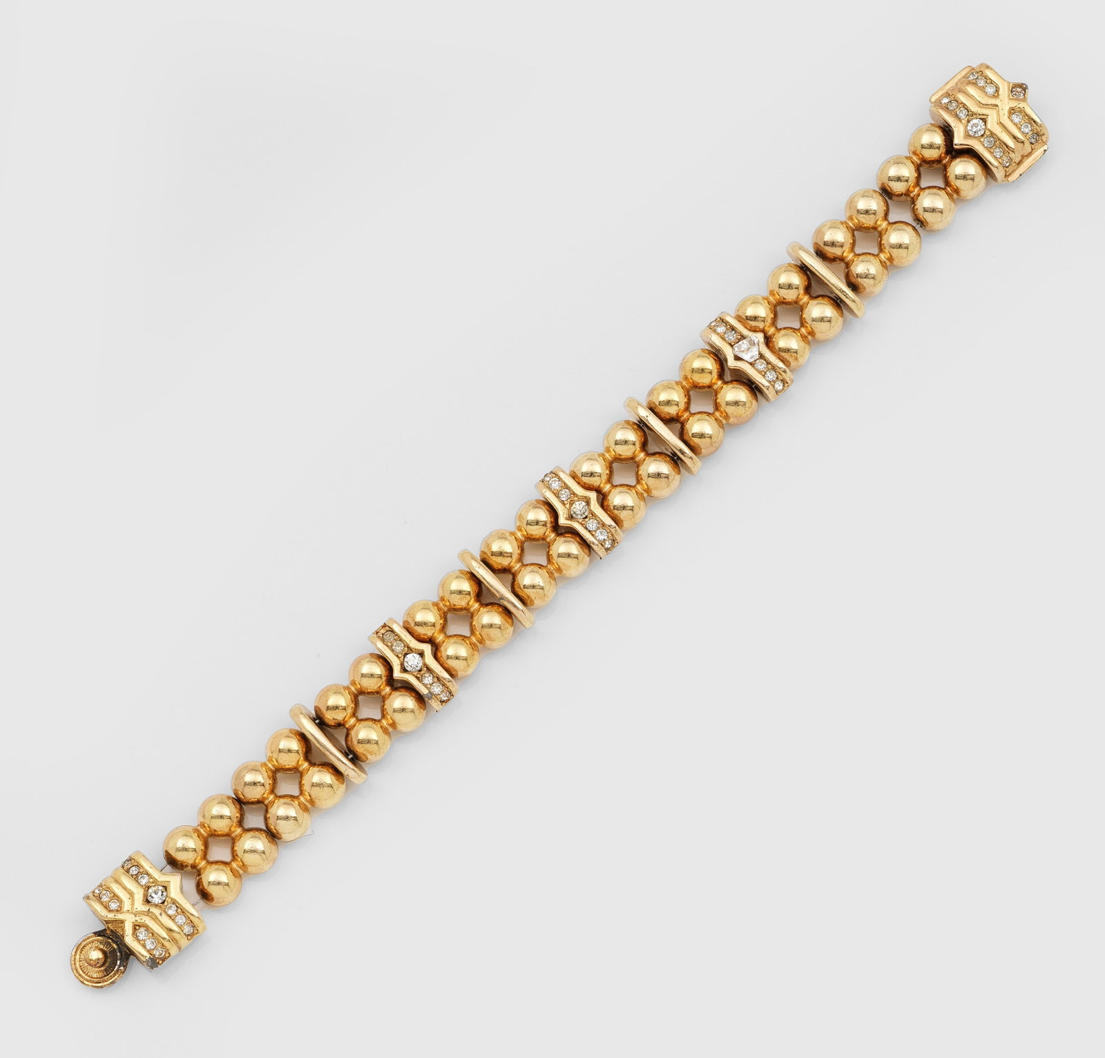 Vintage Armband von Christian Dior aus den 1990er Jahren: Metall, vergoldet. Breites Armband aus in Gruppen zusammengefassten Kugelelementen und unterschiedlichen Stegen, teilw. mit Strassbesatz. Herstellerzeichen. L. 20 cm. A gilt metal Vintage bracelet by 