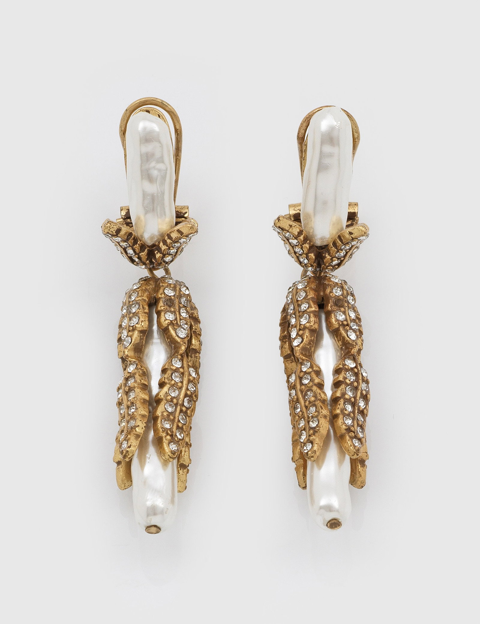 Paar Vintage-Ohrgehänge: Metall, vergoldet sowie Kunstperlen und Strass. Gestreckter Korpus, umgeben von aneinander gereihten Blattmotiven. Fehlstellen. Ges-L. 6,5 cm. A pair of gilt metal French Vintage earrings. Flawed. Fra
