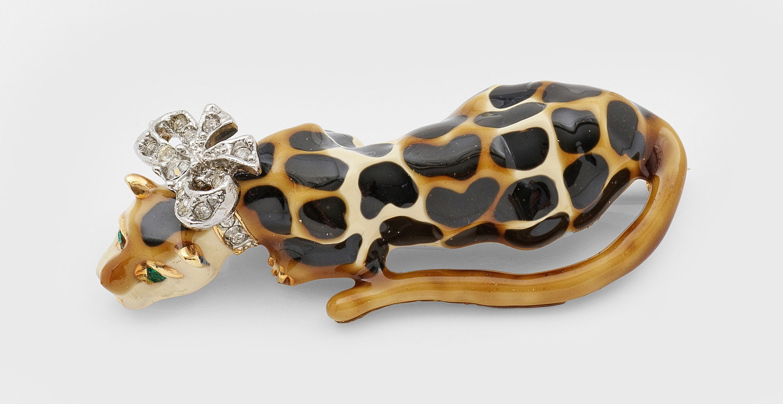 Vintage-Tierbrosche von Kenneth Jay Lane: Metall, vergoldet bzw. farbig emailliert sowie Strasssteine. Plastische Darstellung eines ruhenden Leoparden mit Schleifenhalsband. Herstellerzeichen. L. 5,5 cm. A Vintage gilt metal and enamelled bro