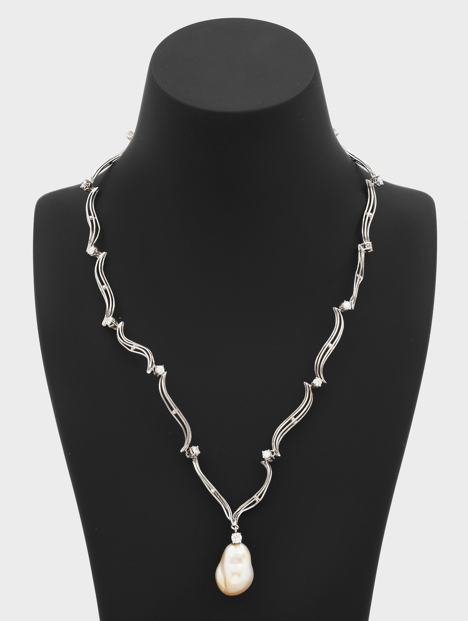 Südsee-Brillant-Collier: Weißgold, gest. 585. Collier-Kette aus volutenförmigen Gliedern in Ajour, unterteilt durch Brillanten von zus. ca. 0,84 ct., abschließend weiß-gelbe Südsee-Zuchtperle in Barockform von ca. 19 mm 