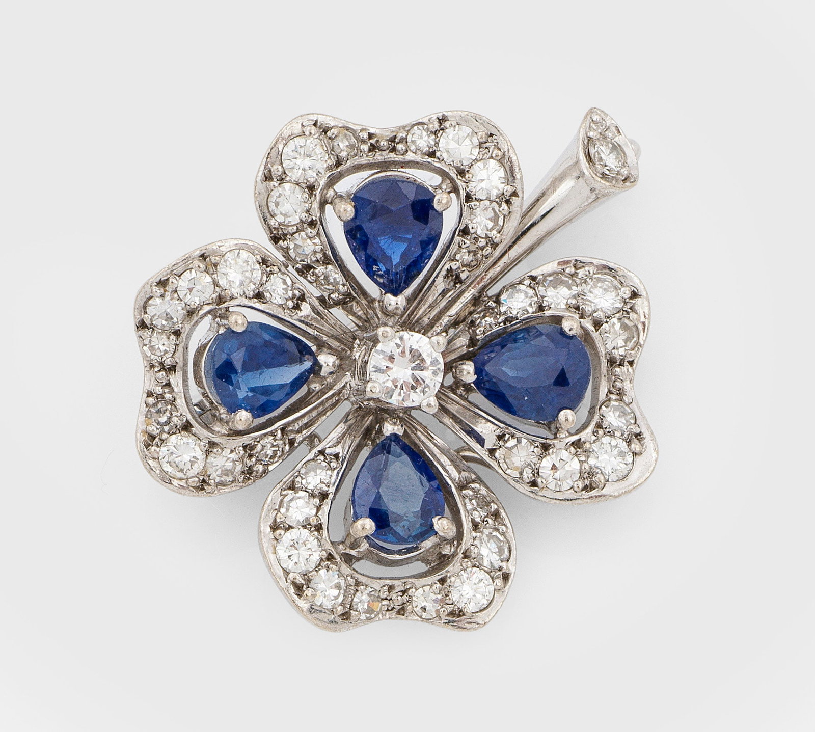 Feine Kleeblatt-Brillant-Brosche mit Saphiren: Weißgold, gest. 750. Besetzt mit 4 royalblauen Saphir-Tropfen von zus. ca. 1,00 ct. und Brillanten von zus. ca. 0,80 ct.; Gew. ca. 7,00 g. Brooch set with sapphires approx. 1,00 ct. and diamonds appr